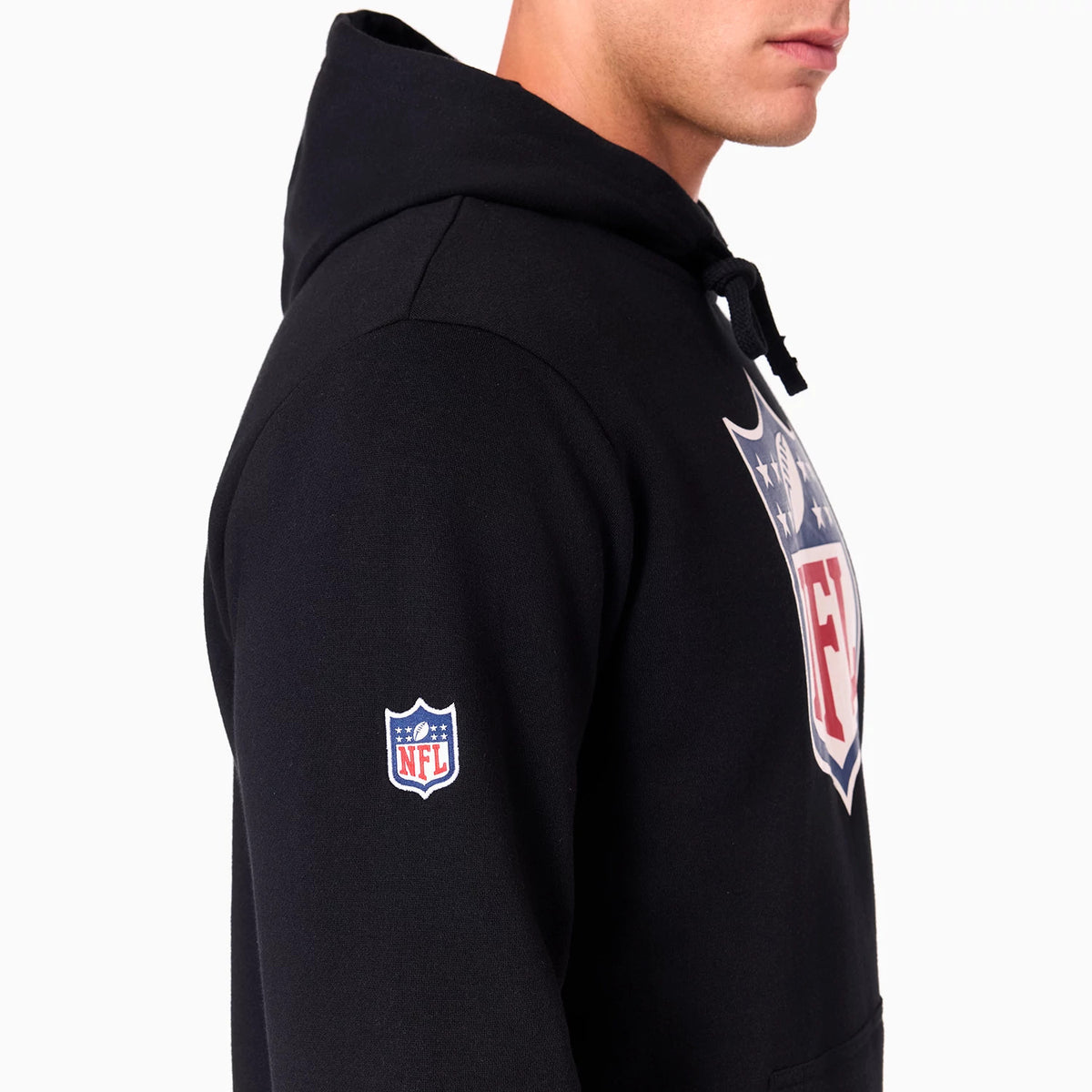 NFL Shield Logo NFL Black Pullover Hoodie, side view showing the large NFL shield logo printed on the chest, a smaller embroidered NFL logo on the upper sleeve, and the edge of the black hood.