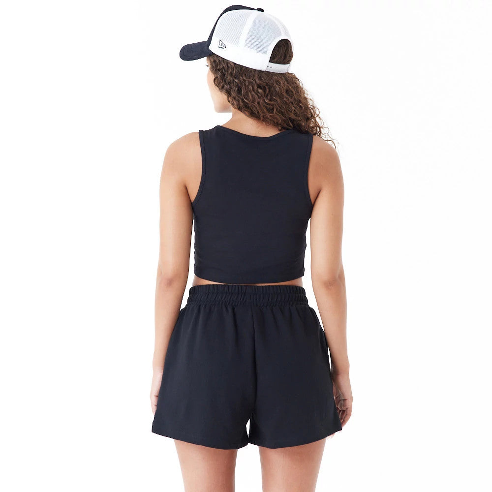 New York Yankees Womens MLB Lifestyle Black Crop Tank Top, rear view on a model paired with black shorts and a two-tone trucker cap, highlighting the sleeveless design and classic cut of the tank top.