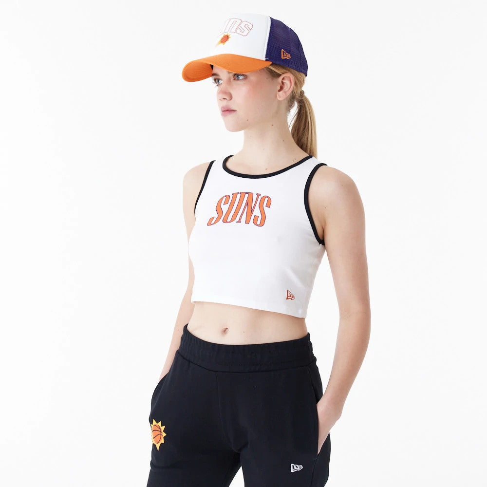 Phoenix Suns Womens NBA Team Wordmark White Crop Tank Top, front view on a model wearing a matching cap and black trousers, featuring bold orange Suns lettering centred on the chest and black piping along the armholes.