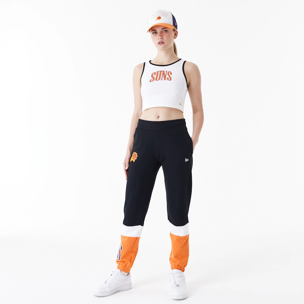 Phoenix Suns Womens NBA Team Wordmark White Crop Tank Top, front view on a model wearing matching joggers and a cap, featuring orange SANS lettering across the chest with black piping along the edges.