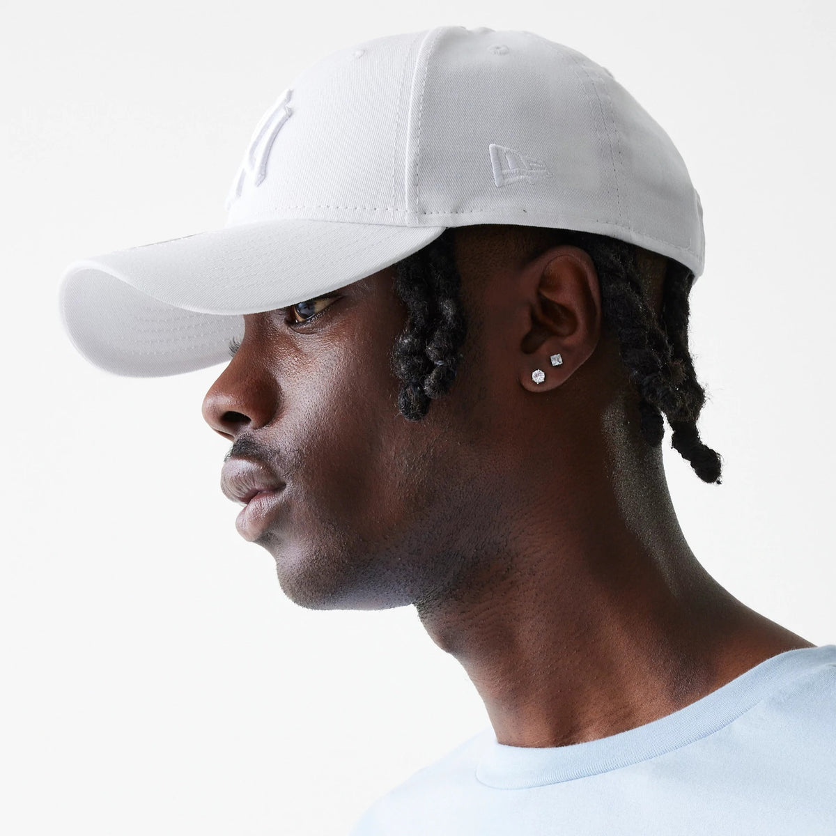 New York Yankees League Essential White New Era 9FORTY Adjustable Cap, side view on a model showing the raised embroidered NY logo on the front panel and the New Era flag logo on the left side of the white crown.