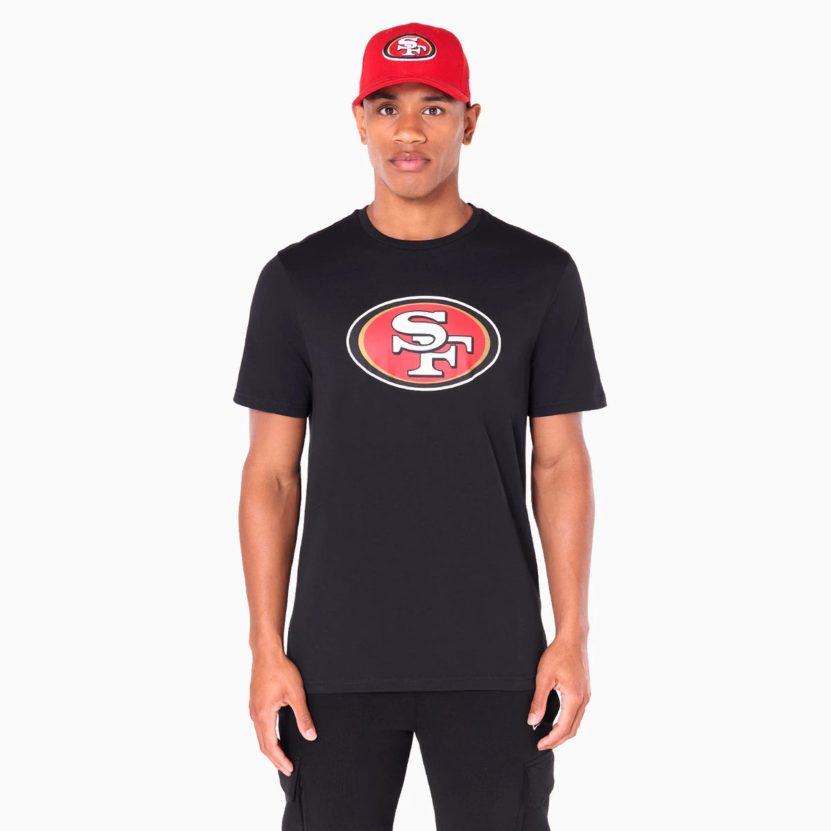 New Era San Francisco 49ers NFL Black T-Shirt, front view showing a large San Francisco 49ers logo printed on the chest in red, gold, and white, worn by a man also wearing a red cap with a raised logo.