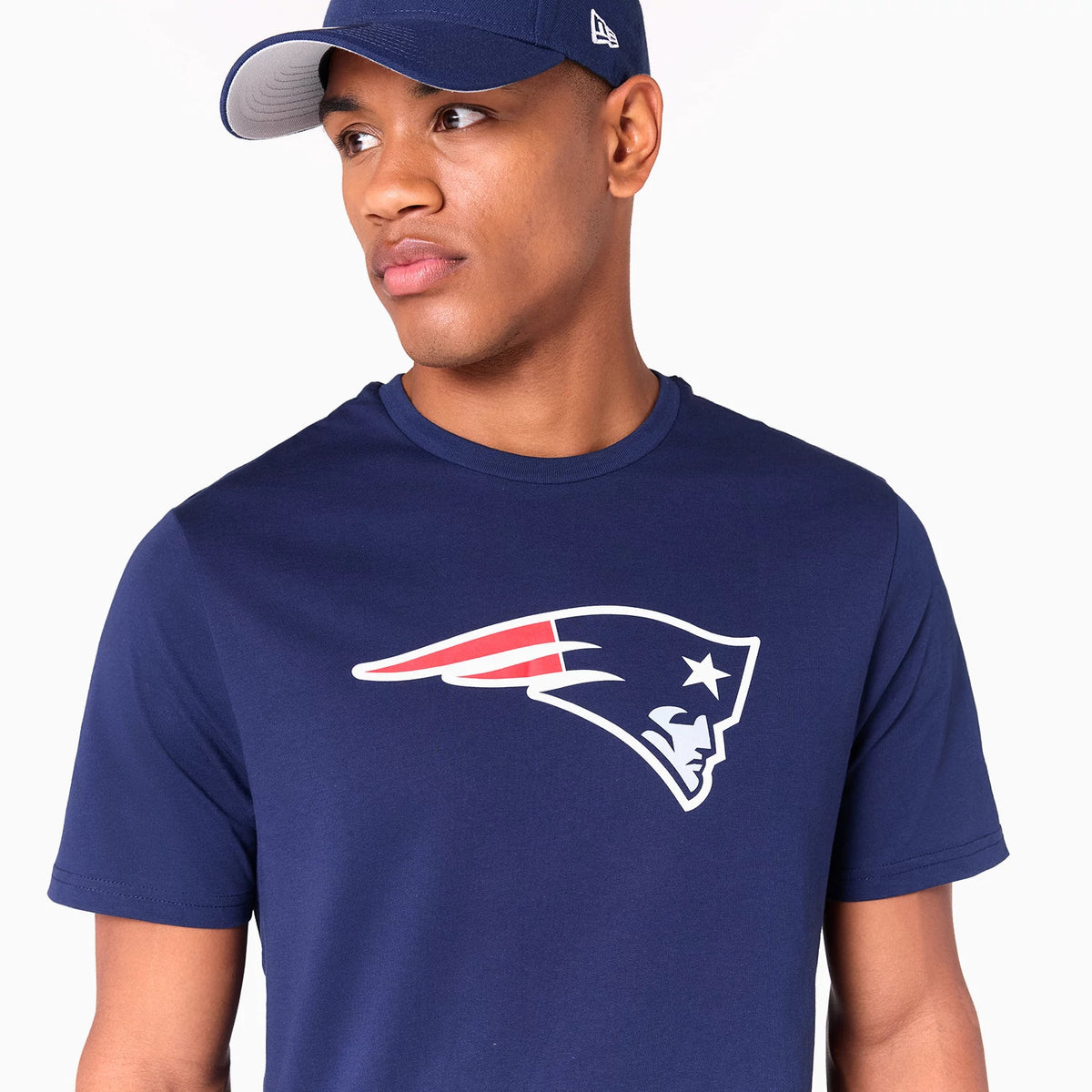 New Era New England Patriots NFL Navy T-Shirt, on-model view showing the short-sleeved navy shirt with the Patriots logo printed in white and red on the chest, paired with a navy cap featuring a raised New Era logo on the side.