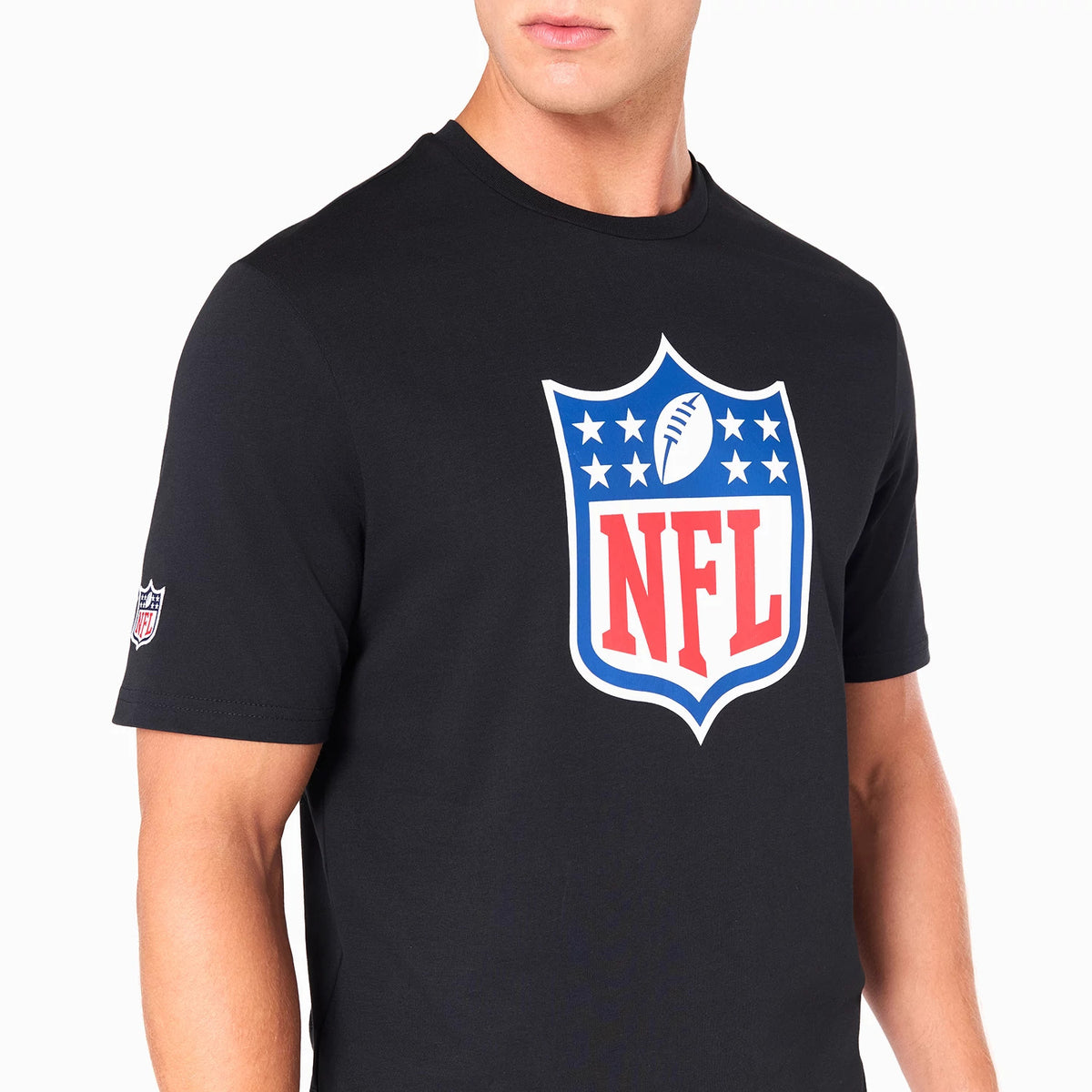 New Era NFL Shield Logo NFL Black T-Shirt, on-model view showing a large shield logo printed in red, white, and blue across the chest, a smaller version of the logo embroidered on the right sleeve, and a plain round neckline.