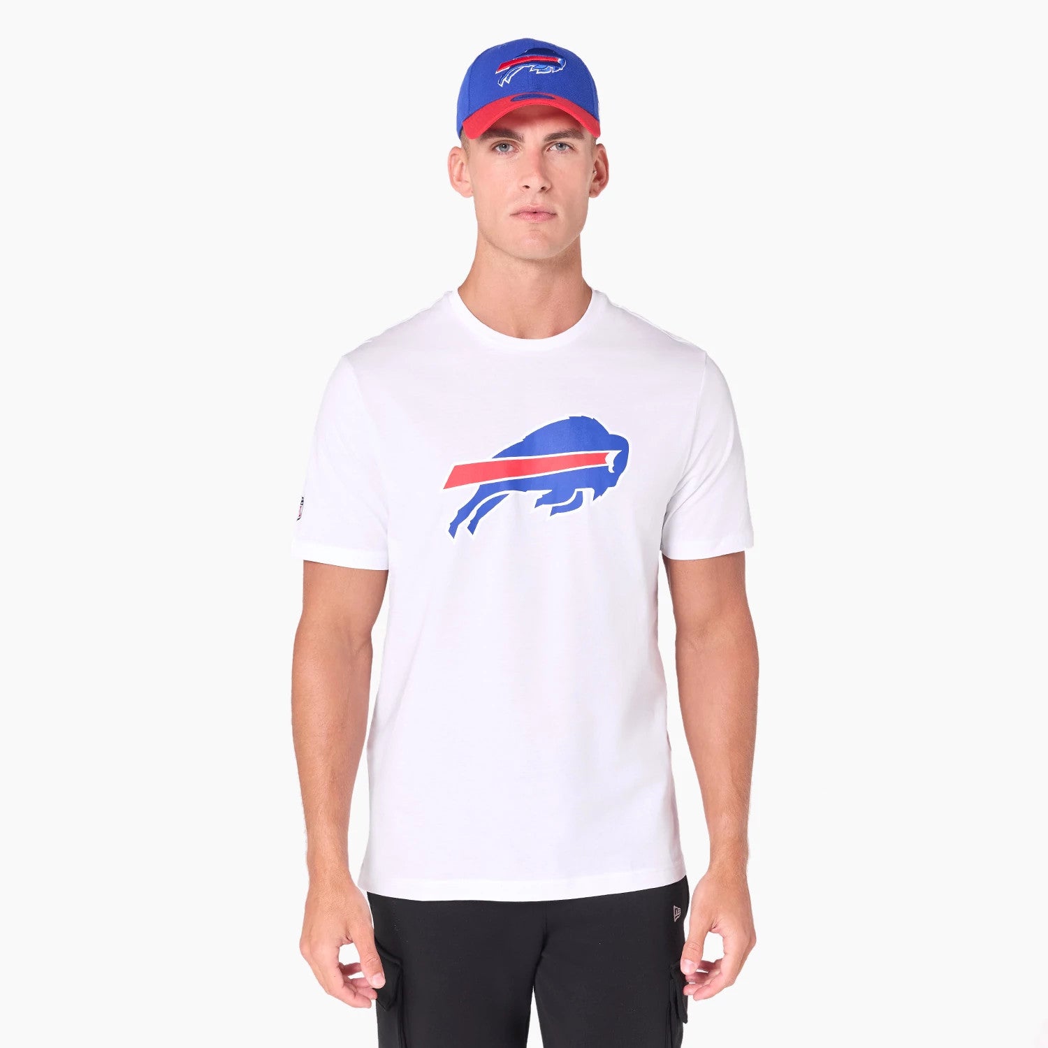 New Era Buffalo Bills NFL White T-Shirt, on-model view showing a large blue and red buffalo logo printed on the chest, a small debossed New Era logo on the sleeve, and the model wearing a blue cap with a matching logo on the front.