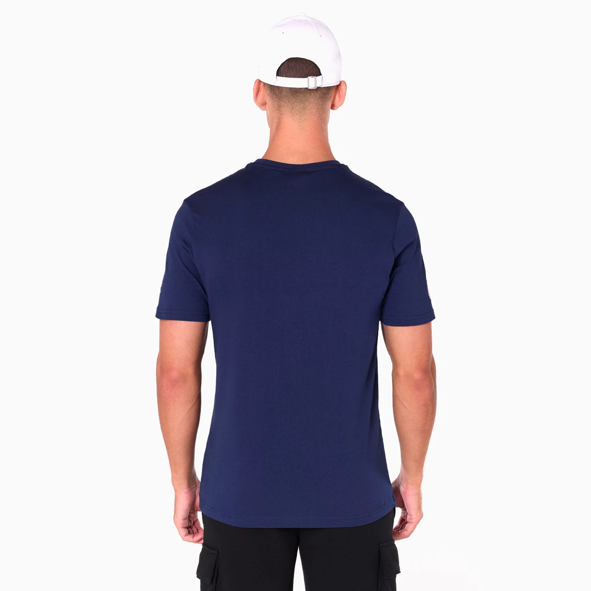New Era LA Rams NFL Navy T-Shirt, rear view showing the plain navy back with short sleeves, worn by a model in a white cap, focusing on the simplicity and fit of the T-shirt from this angle.