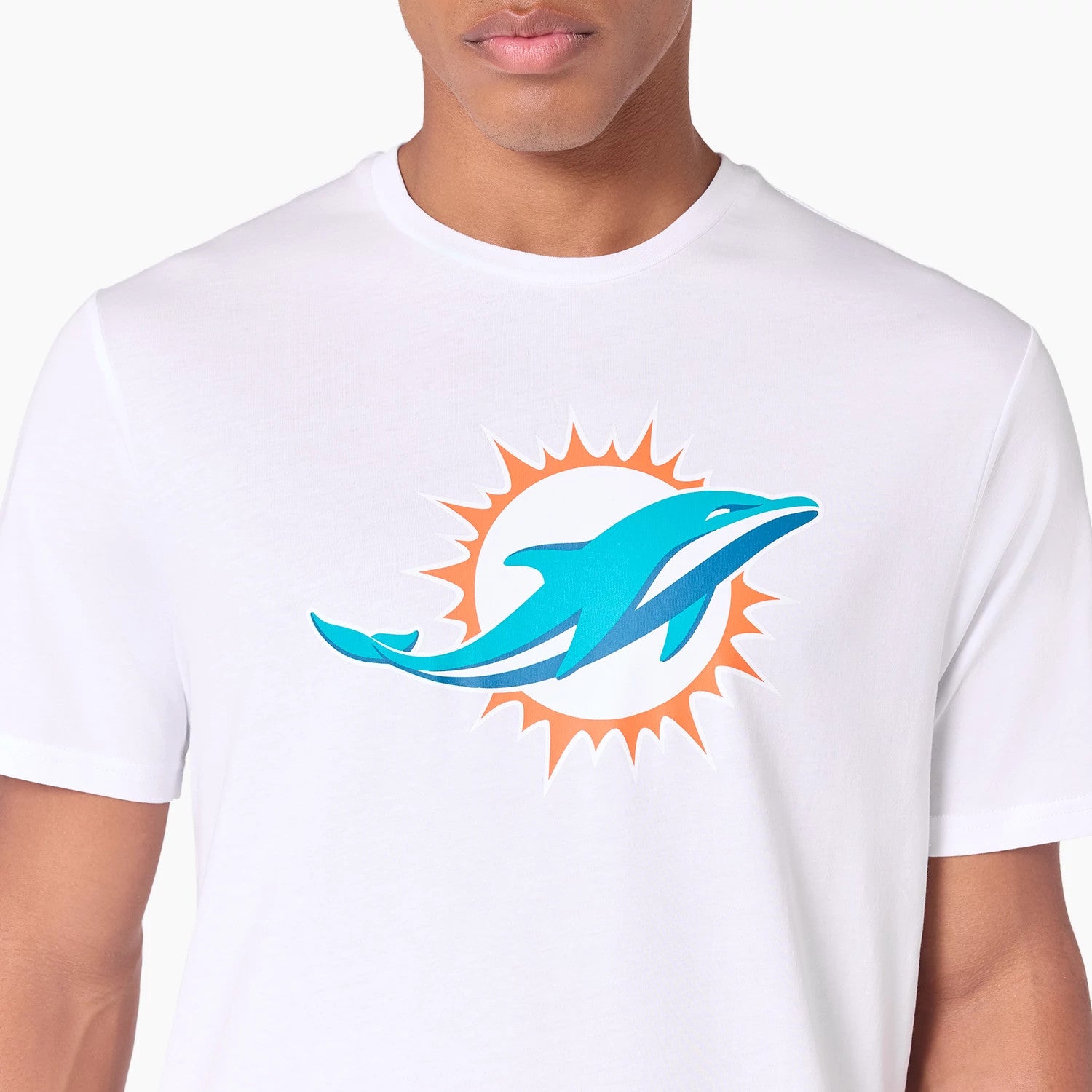 New Era Miami Dolphins NFL White T-Shirt, front view featuring a large teal dolphin graphic with an orange sunburst on the chest, worn by a person with a close-up on the upper torso and shoulders.