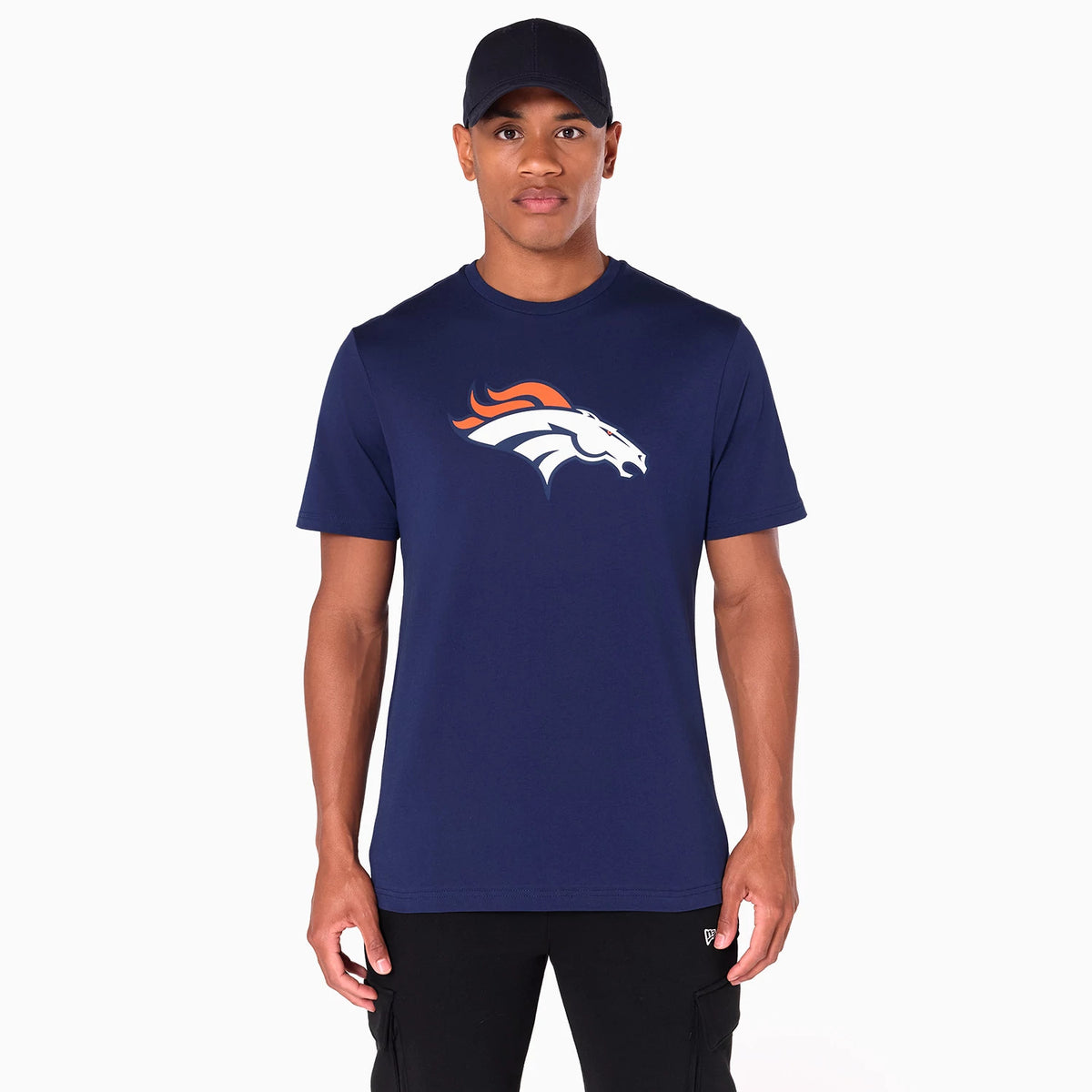 New Era Denver Broncos NFL Navy T-Shirt, on-model view showing a navy t-shirt with a large Denver Broncos logo emblazoned on the chest in white and orange, worn by a person pairing it with a black cap and trousers.