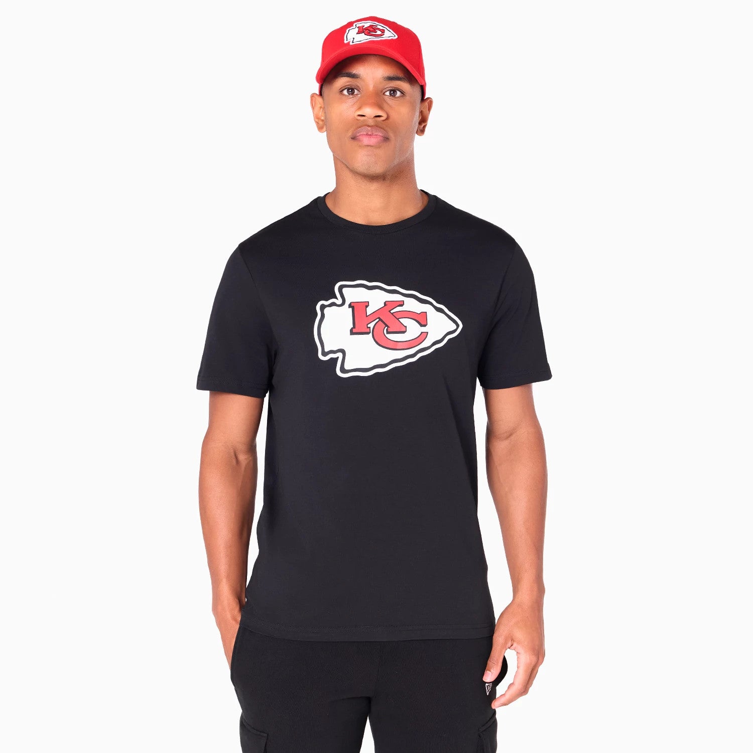 New Era Kansas City Chiefs NFL Black T-Shirt, front view showing a large red and white Chiefs logo centred on the chest, worn by a person in black trousers and a red cap with a white debossed logo.