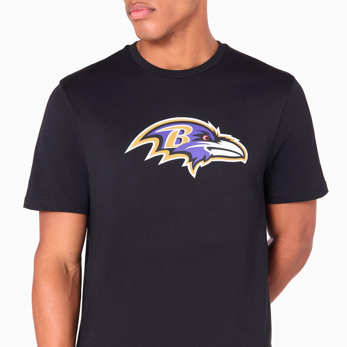 New Era Baltimore Ravens NFL Black T-Shirt, front view displaying a large printed Ravens team logo in purple, gold, and white centred on the chest against the plain black shirt worn by a model.