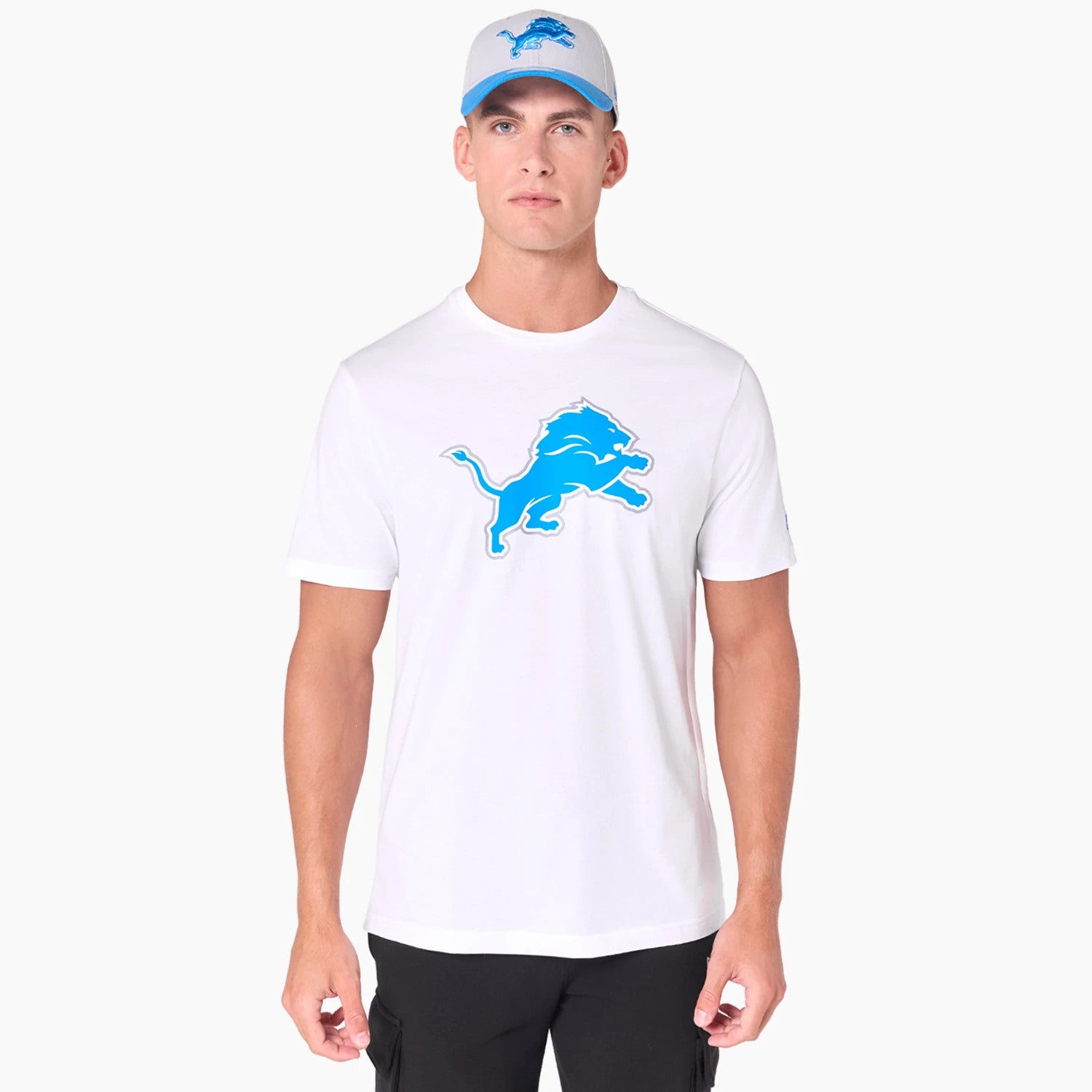 New Era Detroit Lions NFL White T-Shirt, front view showing a blue printed lion logo centred on the chest, worn by a model with a matching white cap featuring the same blue lion logo on the front panel.