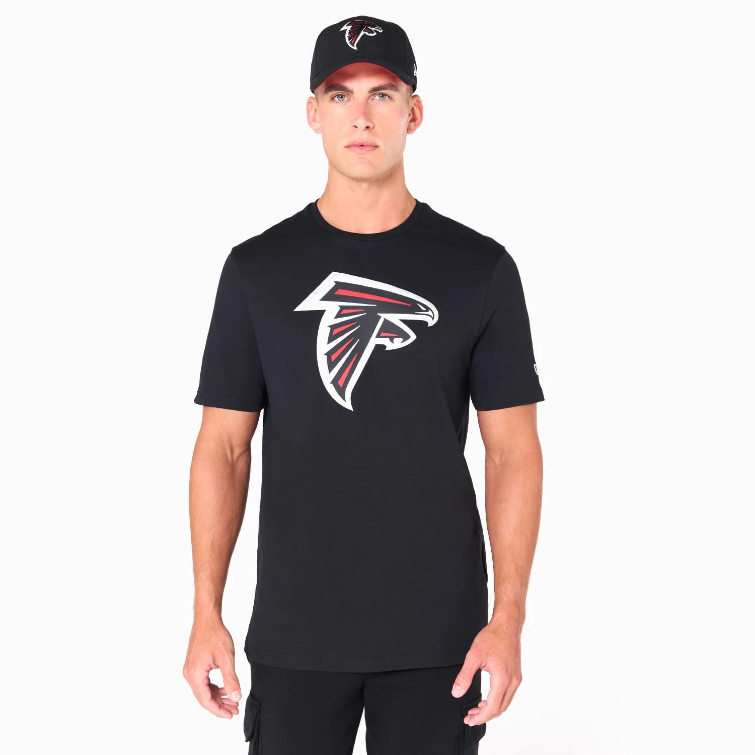 New Era Atlanta Falcons NFL Black T-Shirt, on-model view showing the black T-shirt with a large white and red Falcons logo centred on the chest, paired with a black cap featuring a raised Falcons logo on the front.