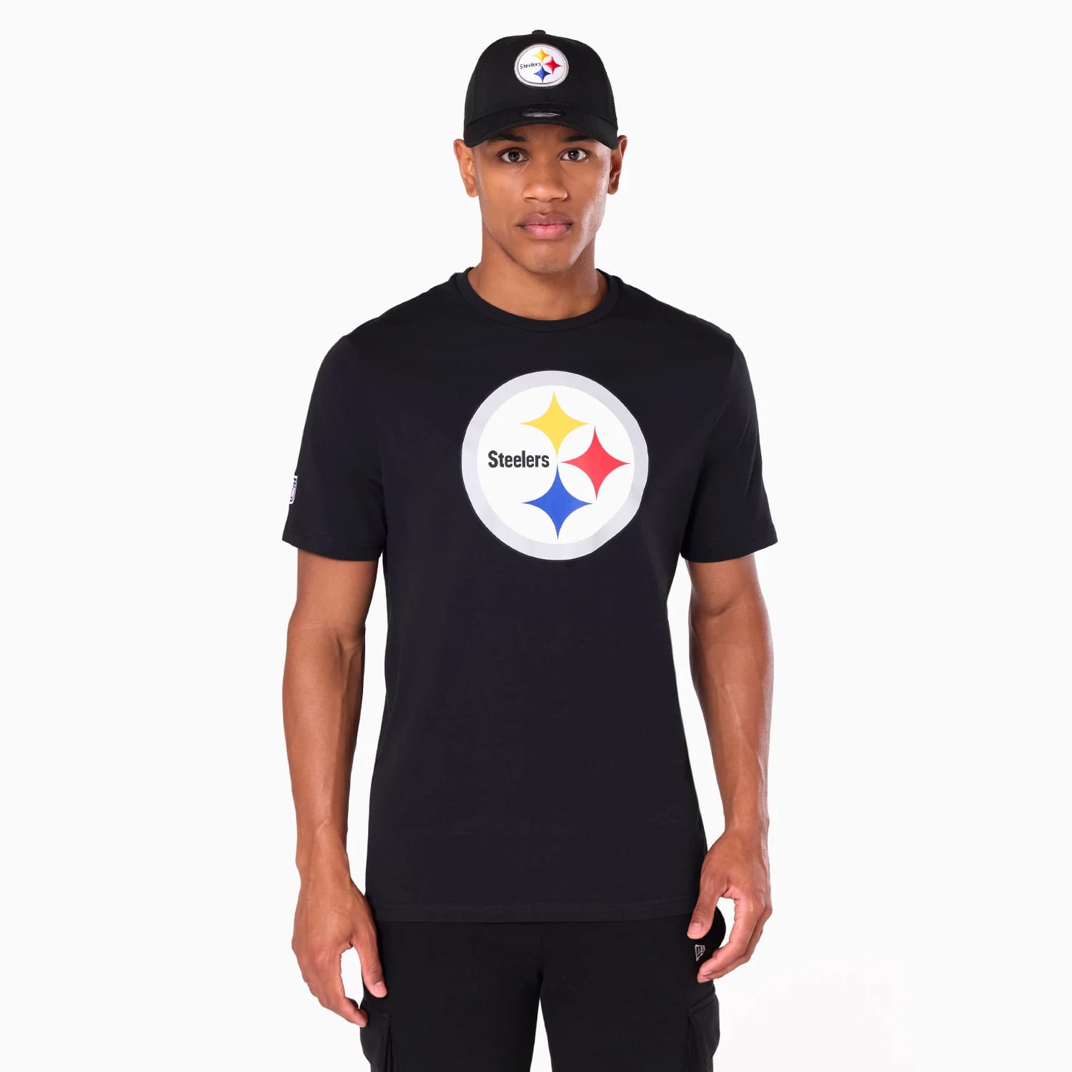 New Era Pittsburgh Steelers NFL Black T-Shirt, on-model view showing the large circular Steelers logo printed on the chest in contrasting colours, worn by a person also in a matching black cap with an embroidered Steelers logo on the front.