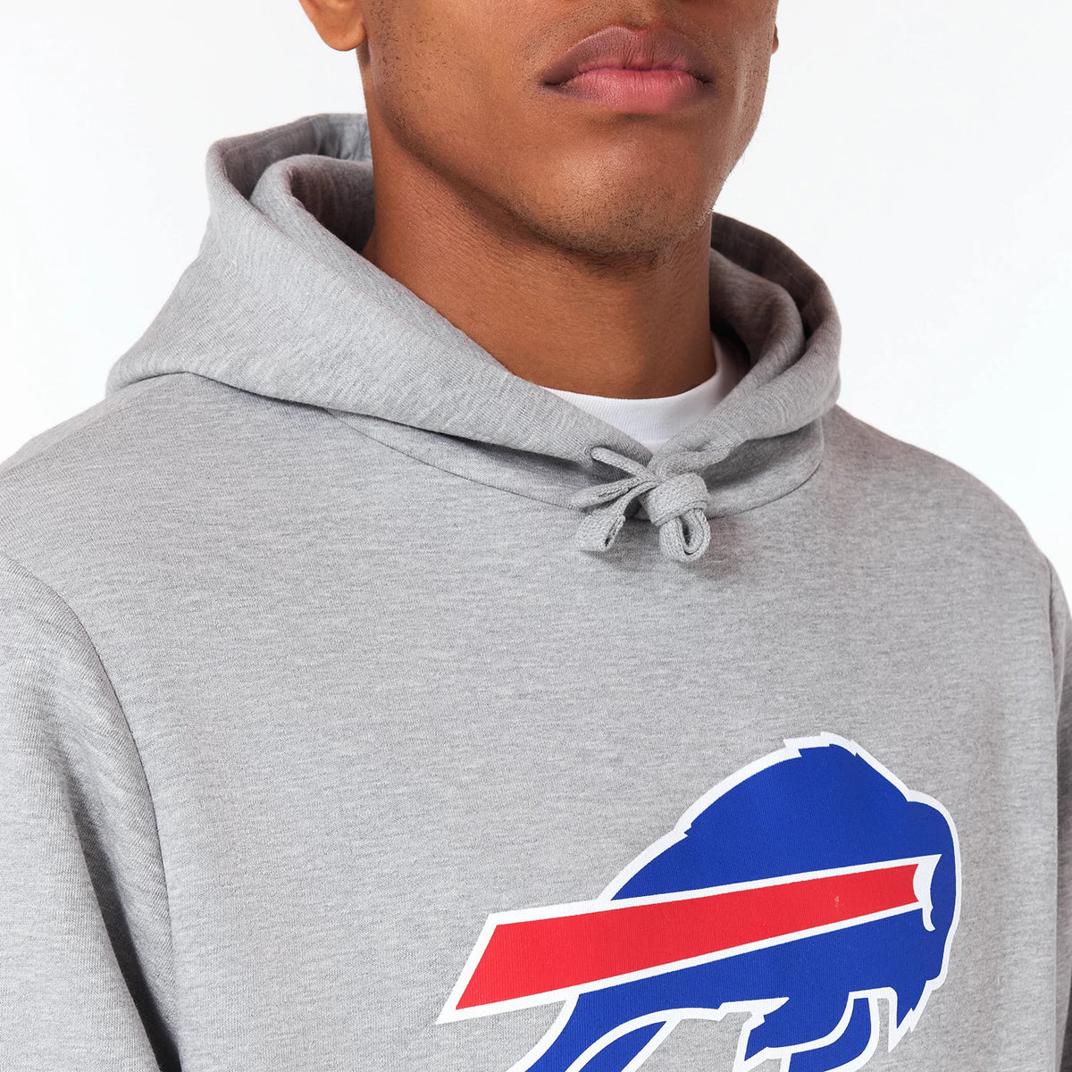 New Era Buffalo Bills NFL Grey Pullover Hoodie, front view showing the grey fabric with a blue buffalo graphic and red stripe on the chest, a drawstring hood, and partial view of the person wearing it.