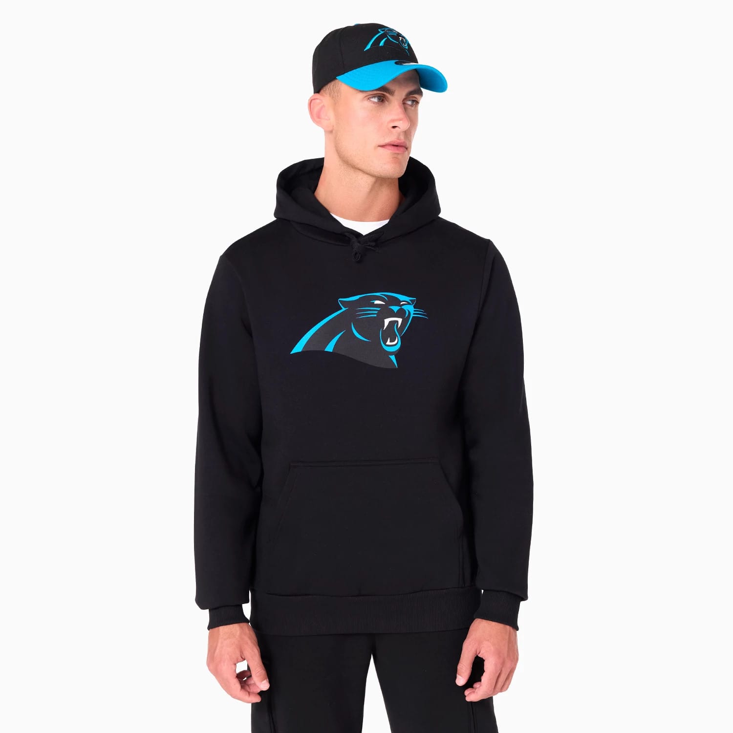 New Era Carolina Panthers NFL Black Pullover Hoodie, on-model view showing a black hoodie with a large blue Carolina Panthers logo on the chest and a model also wearing a black cap with a blue visor and a raised blue logo on the front.