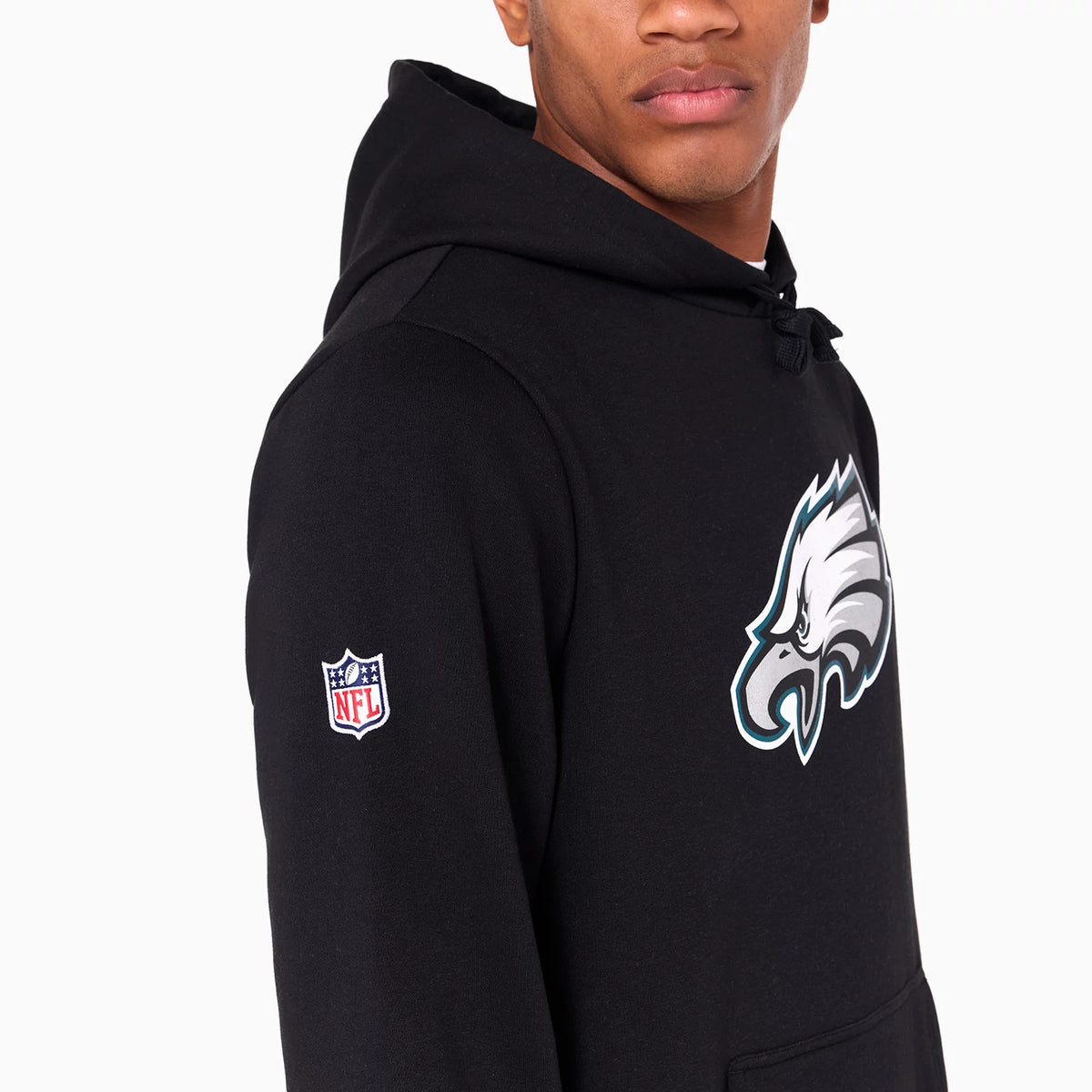 New Era Philadelphia Eagles NFL Black Pullover Hoodie, on-model view showing the black hoodie with a raised Philadelphia Eagles logo on the front, an NFL logo patch on the left sleeve, and a drawstring hood.
