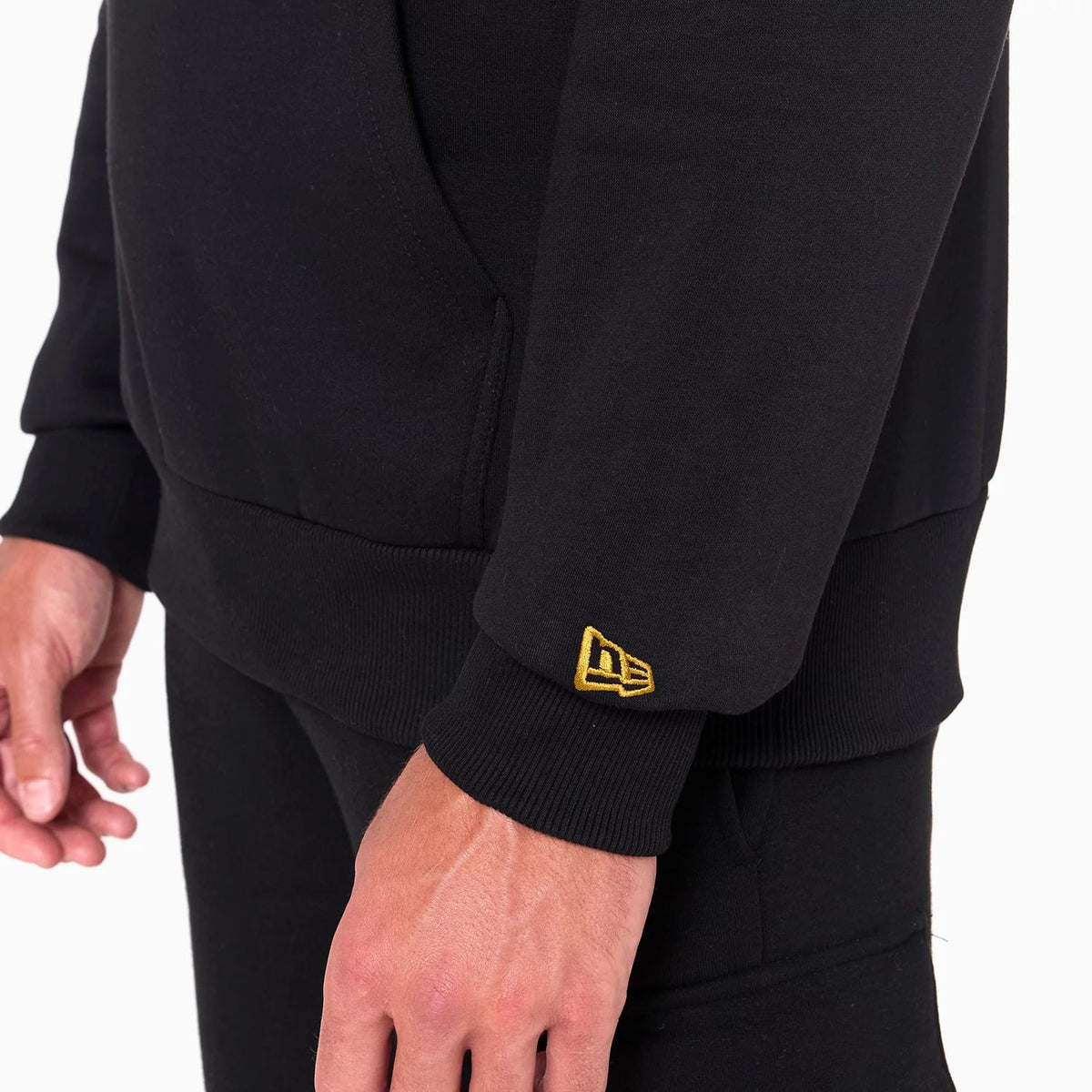 New Era New Orleans Saints NFL Black Pullover Hoodie, three-quarter view showing a black sleeve with a raised yellow New Era logo on the cuff, a kangaroo pocket on the front, and ribbed hem detail at the waist.