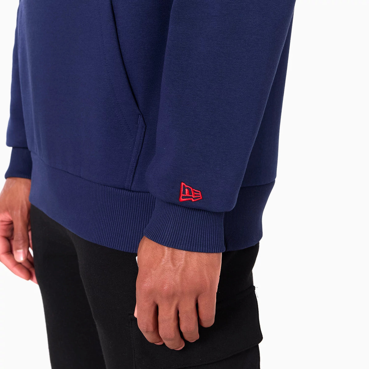 New Era New England Patriots NFL Navy Pullover Hoodie, side view showing a deep navy body with ribbed cuffs and hem, a raised red New Era logo embroidered on the cuff of the sleeve.
