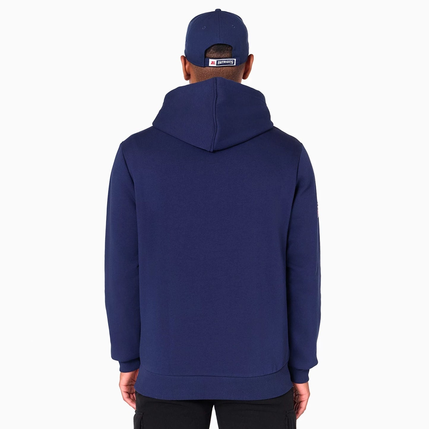 New Era New England Patriots NFL Navy Pullover Hoodie, rear view showing the deep navy colour with a large hood in the middle, worn by a person wearing a matching cap displaying a patch above the back opening.