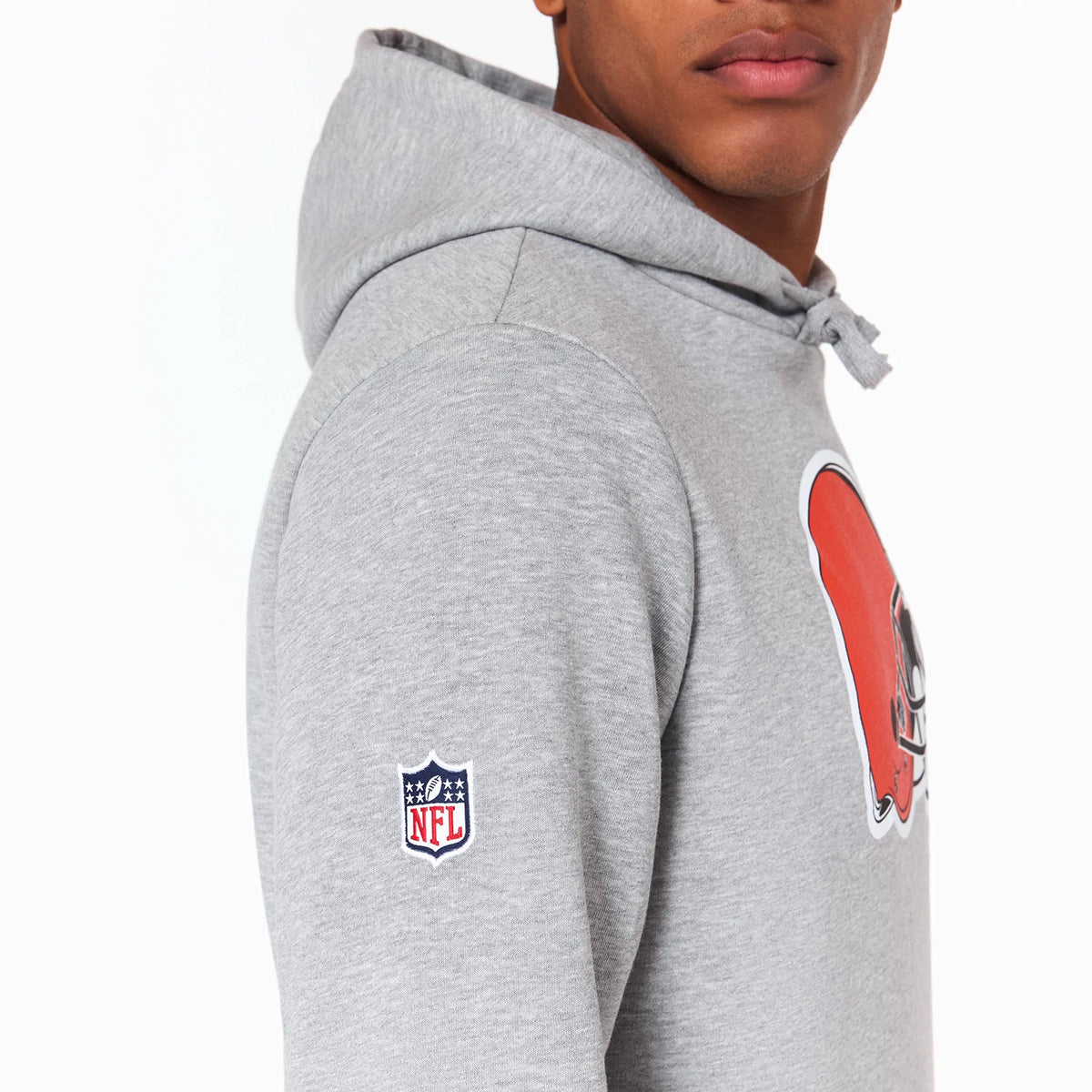 New Era Cleveland Browns NFL Grey Pullover Hoodie, side view showing the grey hood with drawstrings, an NFL logo embroidered on the sleeve, and a large orange helmet graphic on the chest.