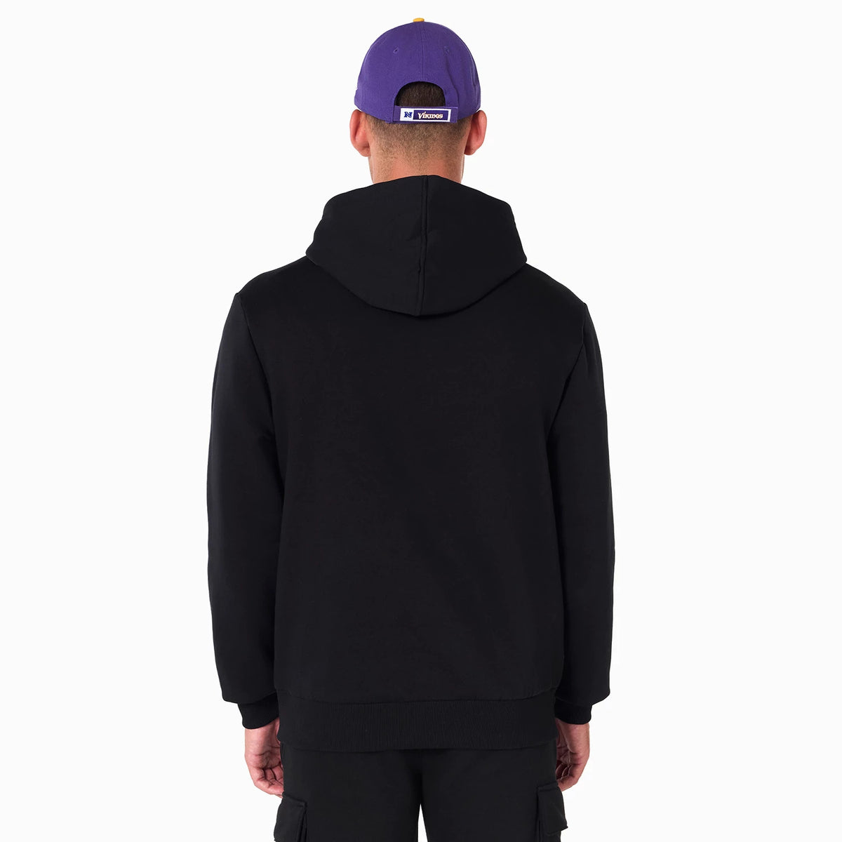 New Era Minnesota Vikings NFL Black Pullover Hoodie, rear view showing the plain black back with a hood, worn by a model with a purple cap featuring a debossed Vikings logo on the back strap.