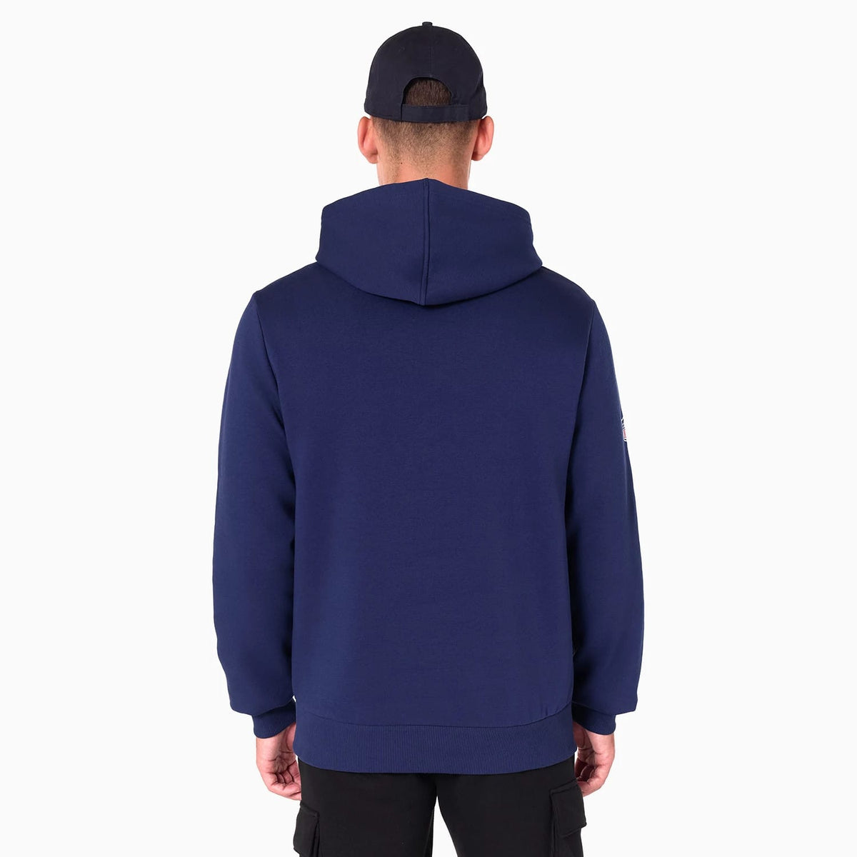 New Era Tennessee Titans NFL Navy Pullover Hoodie, rear view showing the dark navy fabric with a spacious hood and long sleeves, worn by a model in black trousers and a black cap, featuring a small logo on the left sleeve.
