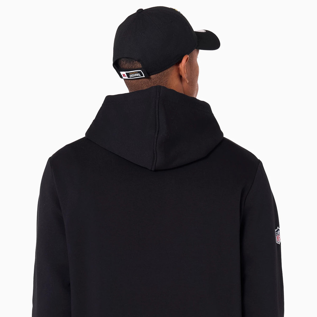 New Era Jacksonville Jaguars NFL Black Pullover Hoodie, rear view showing the black hood with an NFL logo patch on the right sleeve and a black cap with a debossed logo above the adjustable strap on the back.