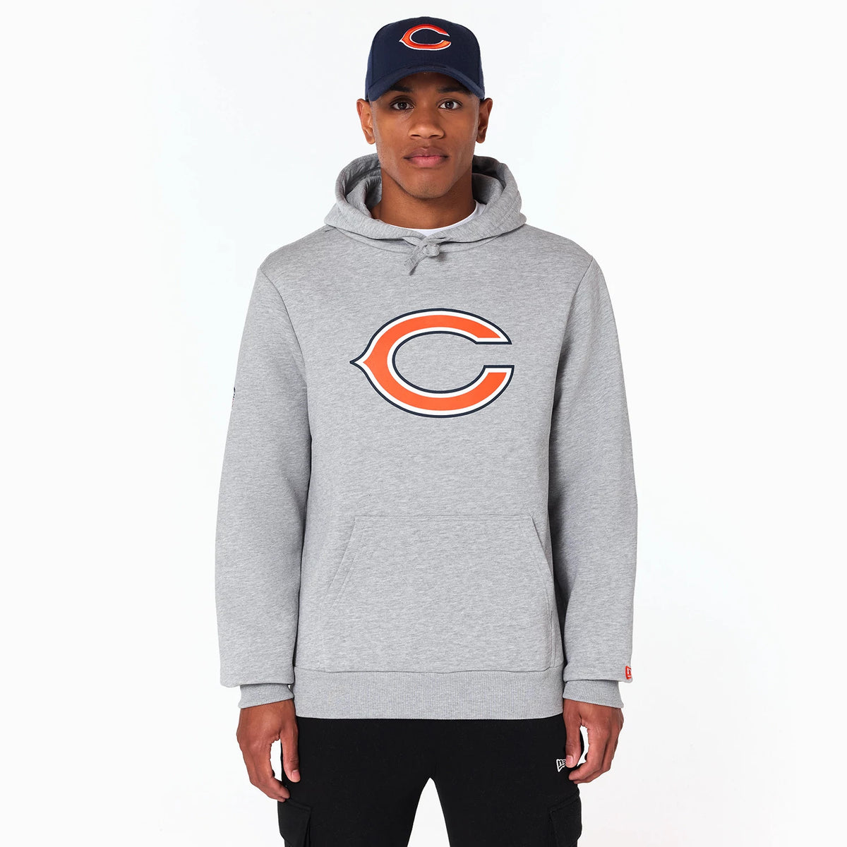 New Era Chicago Bears NFL Grey Pullover Hoodie, on-model view showing the large orange and navy Chicago Bears logo centred on the chest, with a drawstring hood worn by a model in a navy cap featuring a raised team logo.