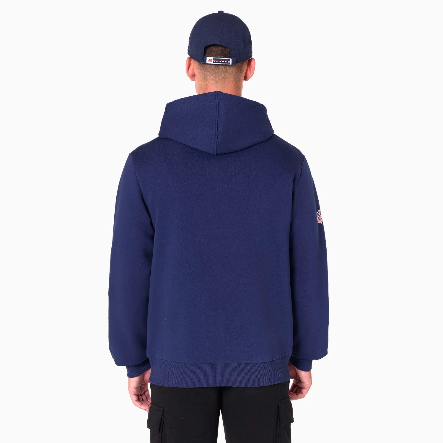 New Era Houston Texans NFL Navy Pullover Hoodie, rear view showing the plain navy back with a spacious hood, the Houston Texans logo patch on the left sleeve, and a matching navy cap worn by the model with a small logo on the back.