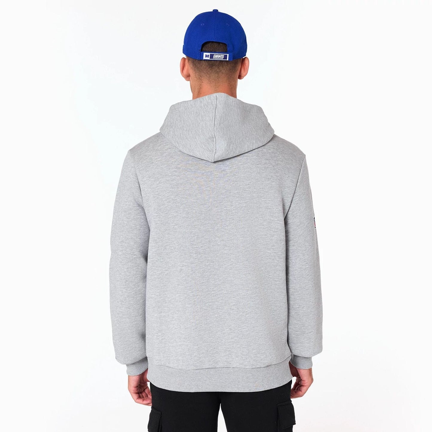 New Era New York Giants NFL Grey Pullover Hoodie, rear view showing the hooded design and relaxed fit, on-model wearing a blue cap with a debossed logo on the back above the grey fabric of the hoodie.