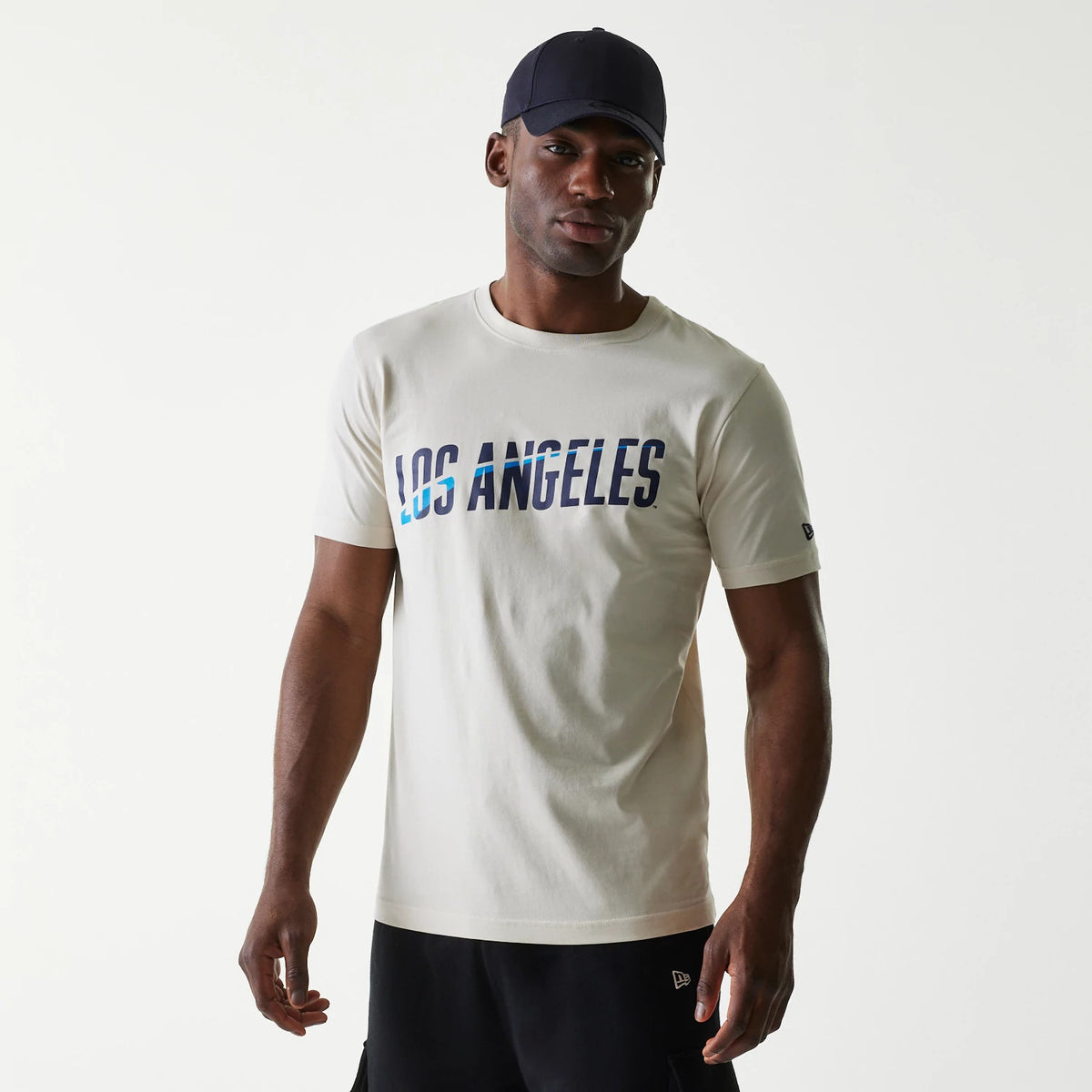 New Era LA Dodgers MLB City Connect Cream T-Shirt, on-model view showing the cream short-sleeve shirt with Los Angeles in blue gradient lettering across the chest and a small embroidered New Era logo on the left sleeve.