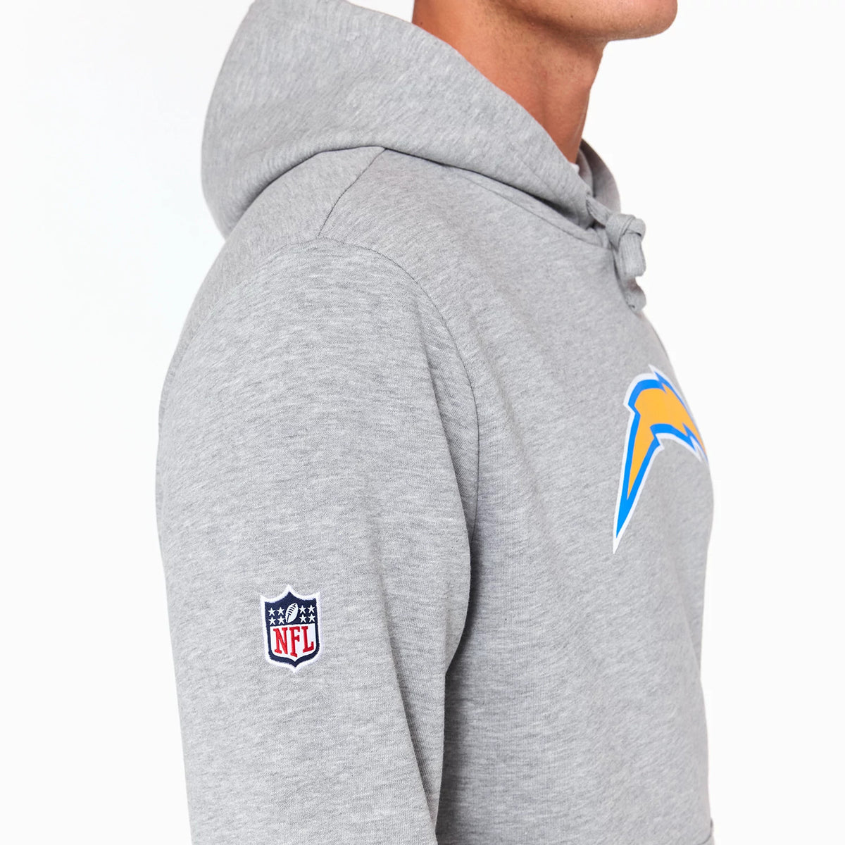 New Era LA Chargers NFL Grey Pullover Hoodie, side view showing the grey fabric with a raised Chargers logo in blue and yellow on the chest, an embroidered NFL logo on the sleeve and a drawstring hood at the back.