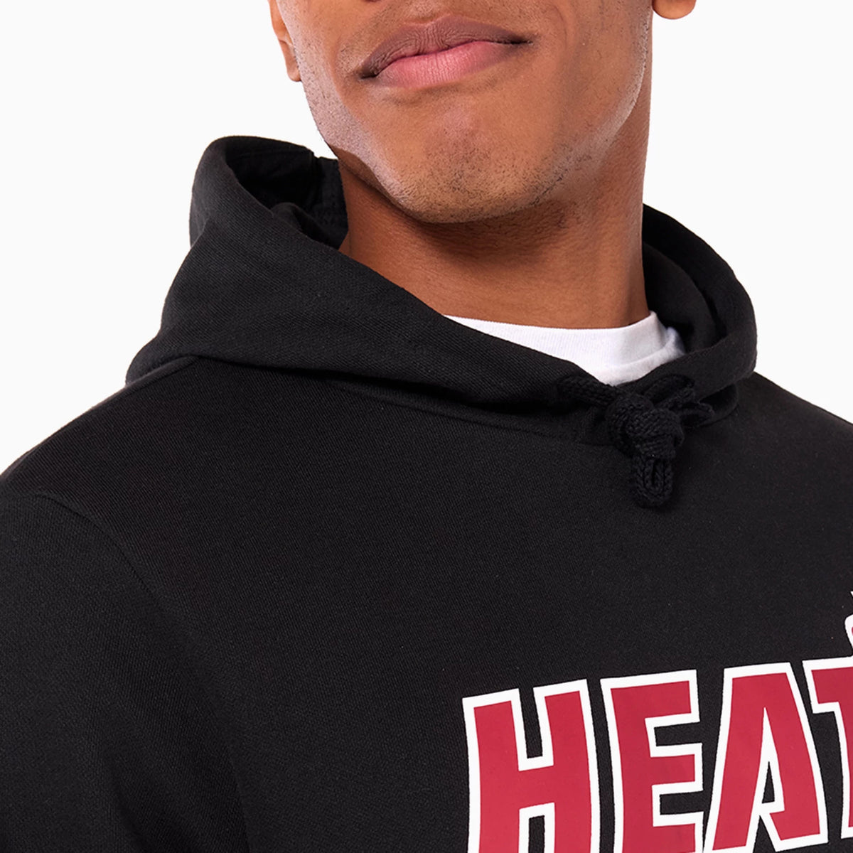 New Era Miami Heat NBA Black Pullover Hoodie, on-model view showing the black hood with black drawstrings, the bold red HEAT text across the chest in white outline, and a portion of the collar and neckline.