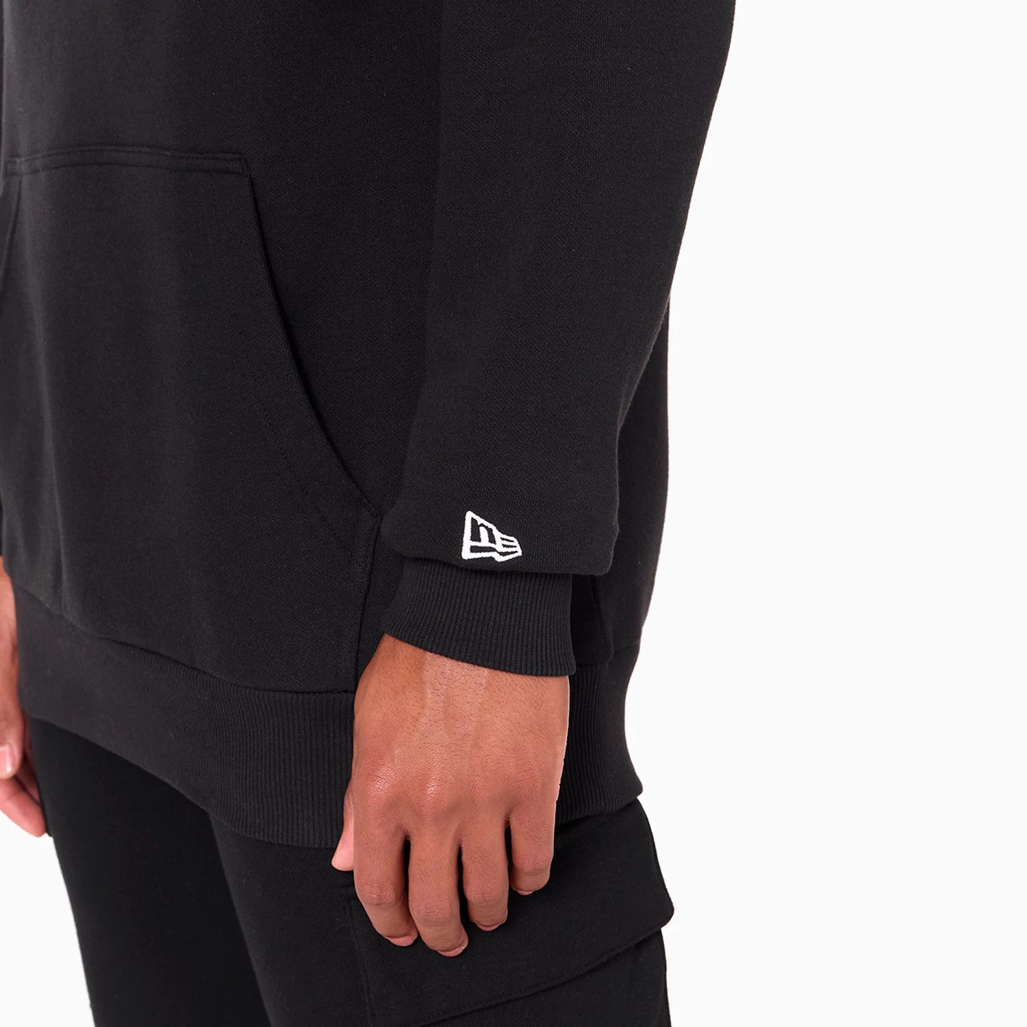 New Era Miami Heat NBA Black Pullover Hoodie, side view showing the lower sleeve with a raised New Era logo embroidered near the ribbed cuff and a kangaroo pocket on the black fabric.