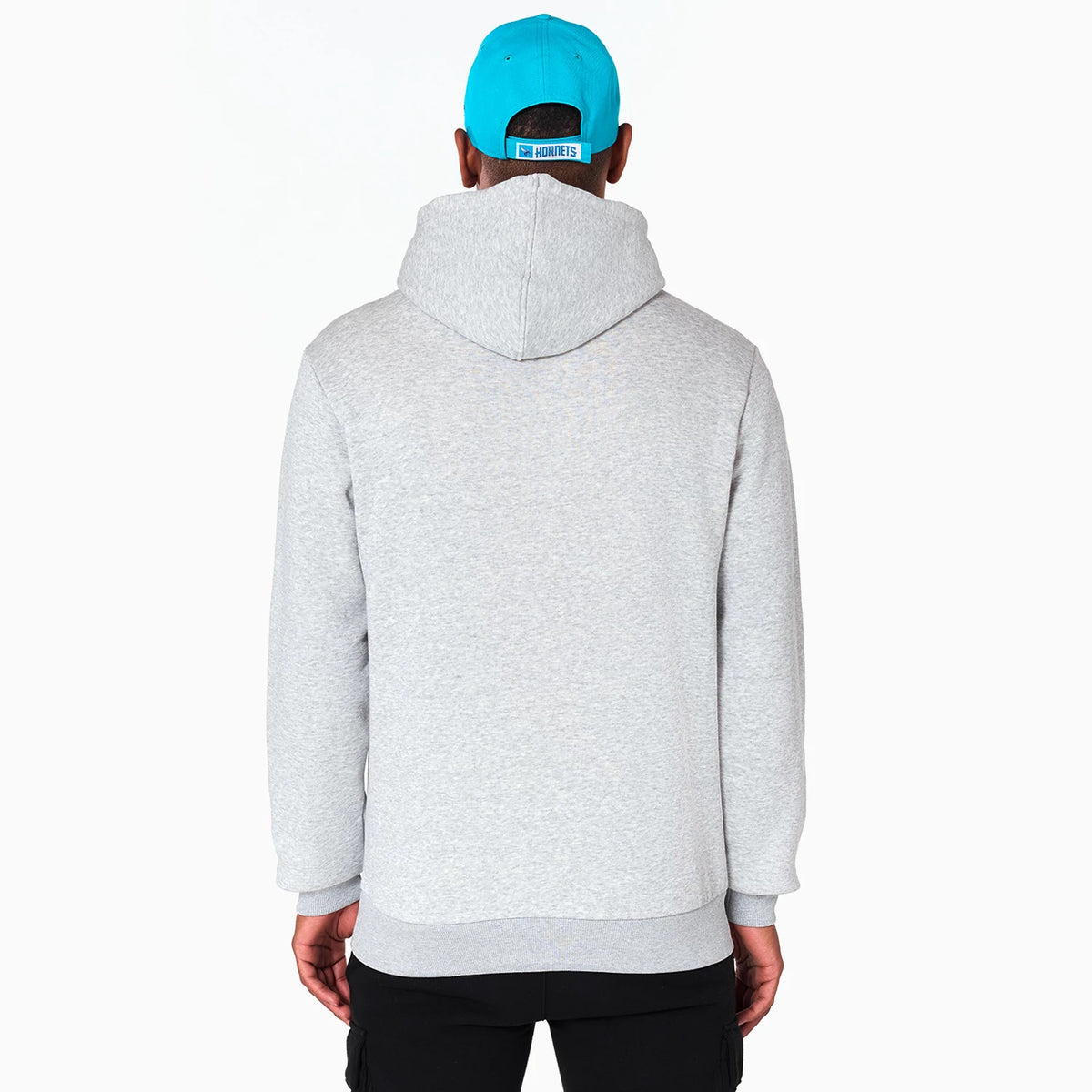 New Era Charlotte Hornets NBA Grey Pullover Hoodie, back view showing the plain grey material with a loose-fitting hood, worn by a model also wearing a blue cap featuring a raised logo above the adjuster strap.