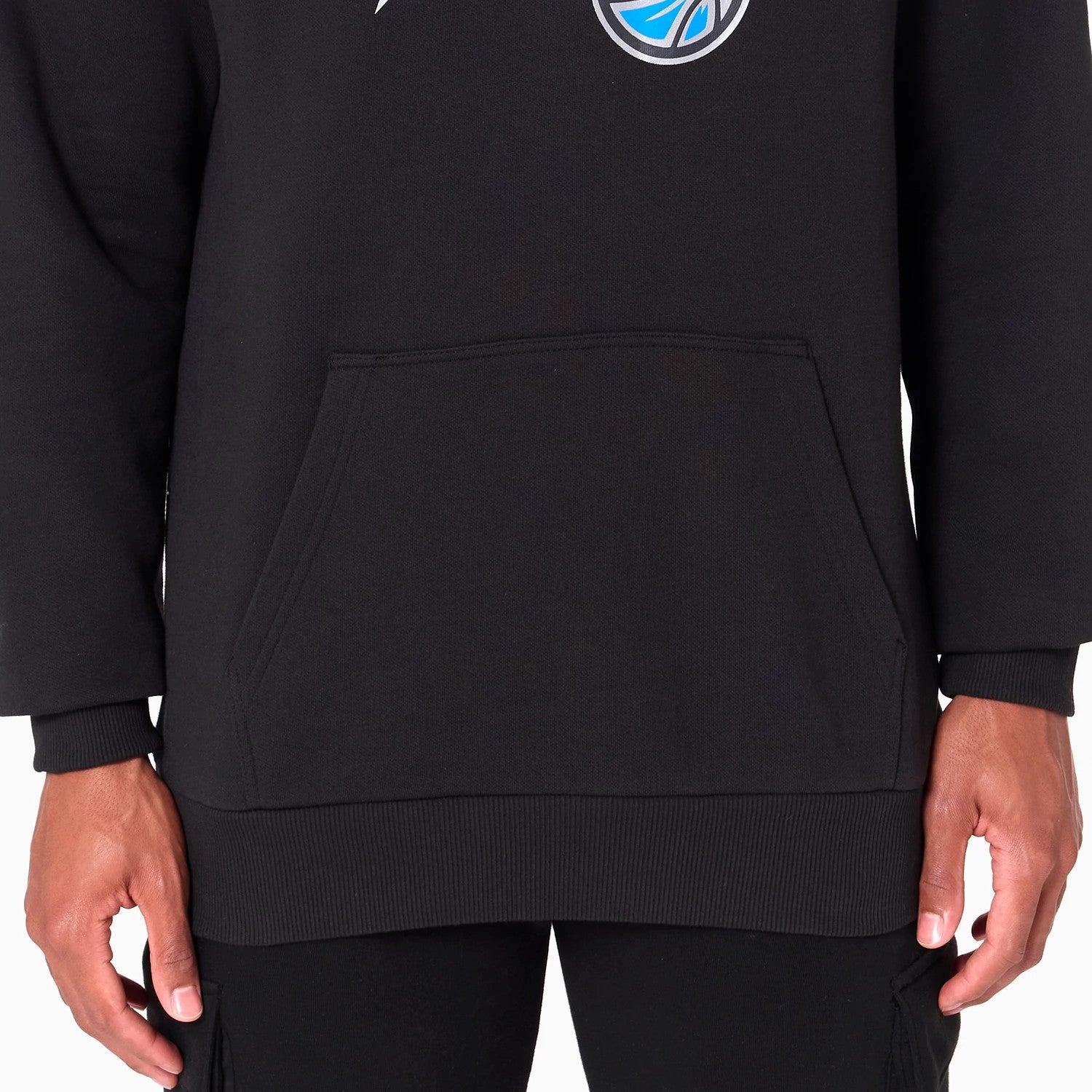 New Era Orlando Magic NBA Black Pullover Hoodie, front view showing the kangaroo pocket at the lower centre and a raised circular Orlando Magic logo in blue and white above it on the black fabric.