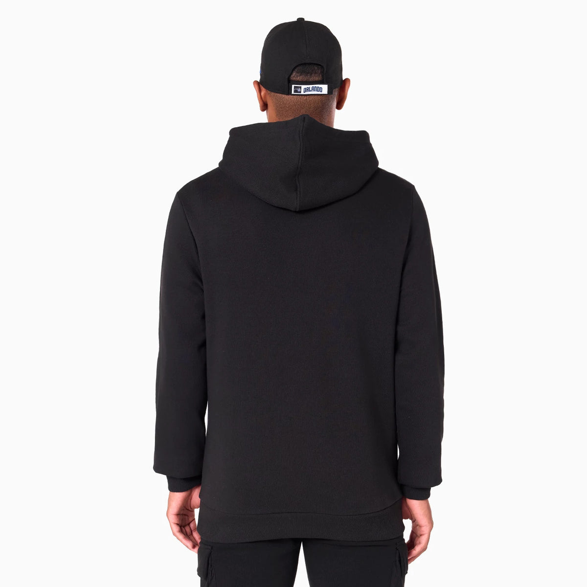New Era Orlando Magic NBA Black Pullover Hoodie, rear view showing the plain black hoodie with a relaxed fit and a spacious hood, on-model with a black cap featuring a raised logo tag above the adjustable strap.