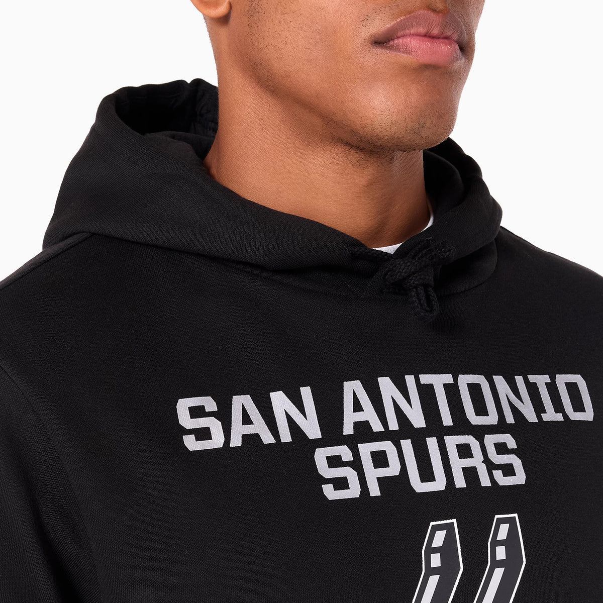 New Era San Antonio Spurs NBA Black Pullover Hoodie, on-model view showing the black hoodie with a drawstring hood and raised white San Antonio Spurs text across the chest above the team logo.