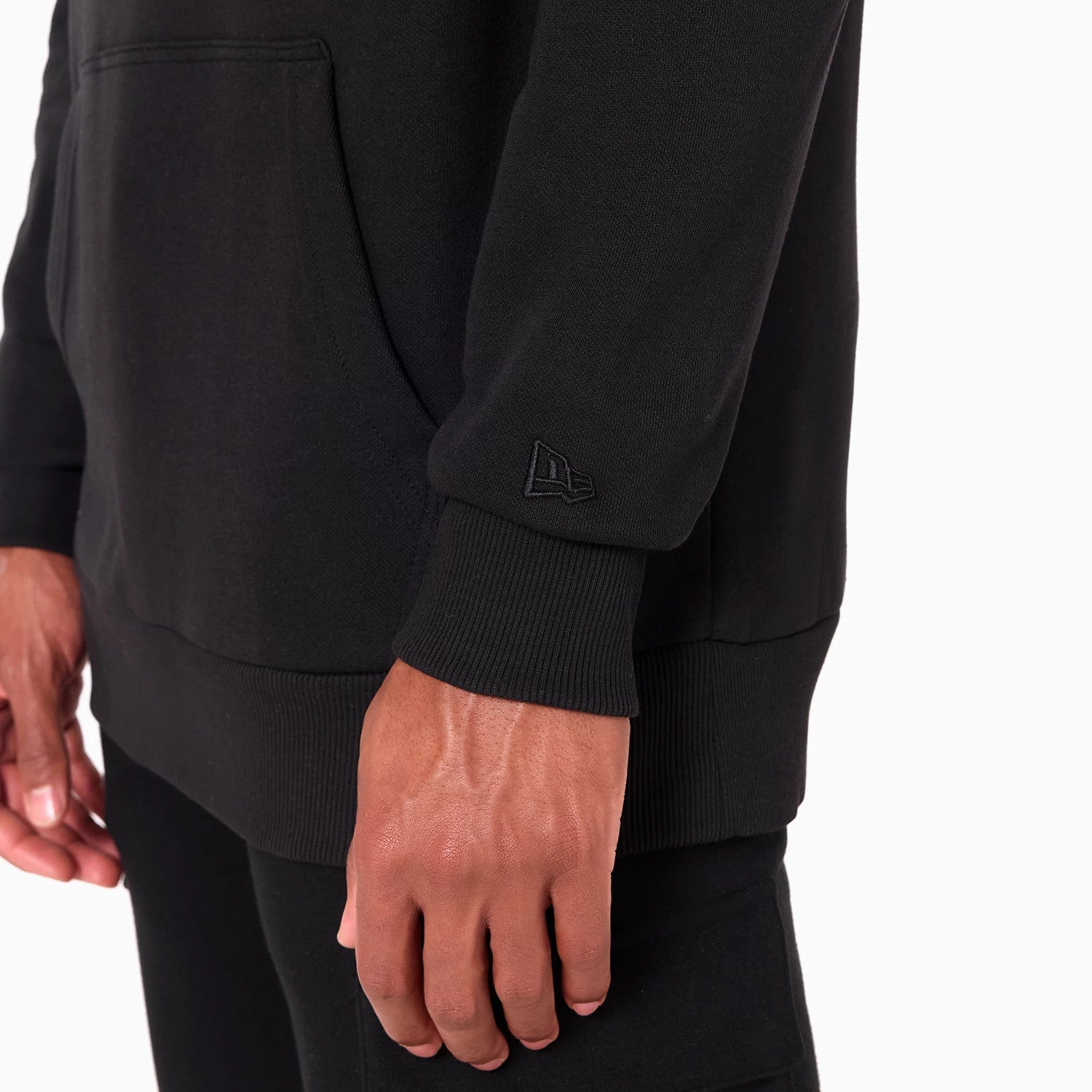 New Era Chicago Bulls NBA Black Pullover Hoodie, side view showing the ribbed cuffs and waistband, the embossed New Era logo on the left sleeve, and the bottom half of the spacious kangaroo pocket.