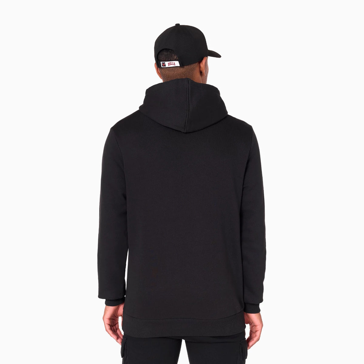 New Era Chicago Bulls NBA Black Pullover Hoodie, rear view showing the plain black design with a hood, long sleeves, and an on-model display, accompanied by a black cap featuring an embroidered white and black NBA logo on the back.