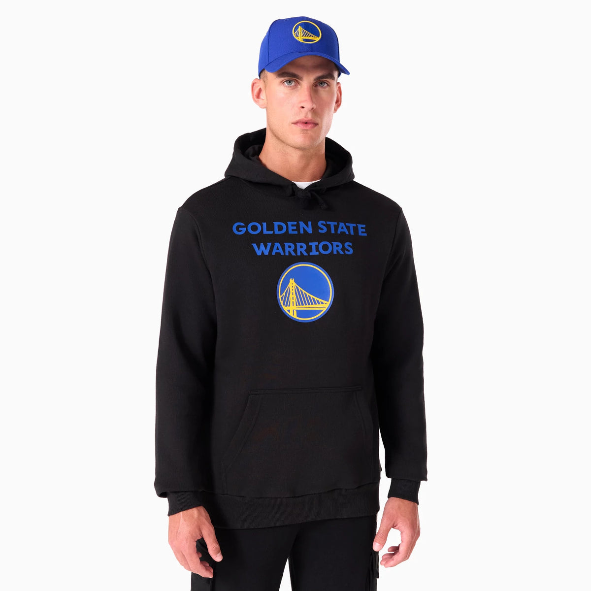 New Era Golden State Warriors NBA Black Pullover Hoodie, on-model view showing a large printed team logo and name in blue and yellow on the front chest, worn with a blue cap featuring a raised Warriors logo.