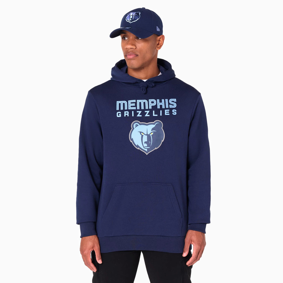 New Era Memphis Grizzlies NBA Navy Pullover Hoodie, on-model view showing the navy hoodie with a front kangaroo pocket, light blue Memphis Grizzlies text above a grizzly bear logo, and a navy cap with the same logo worn by the model.