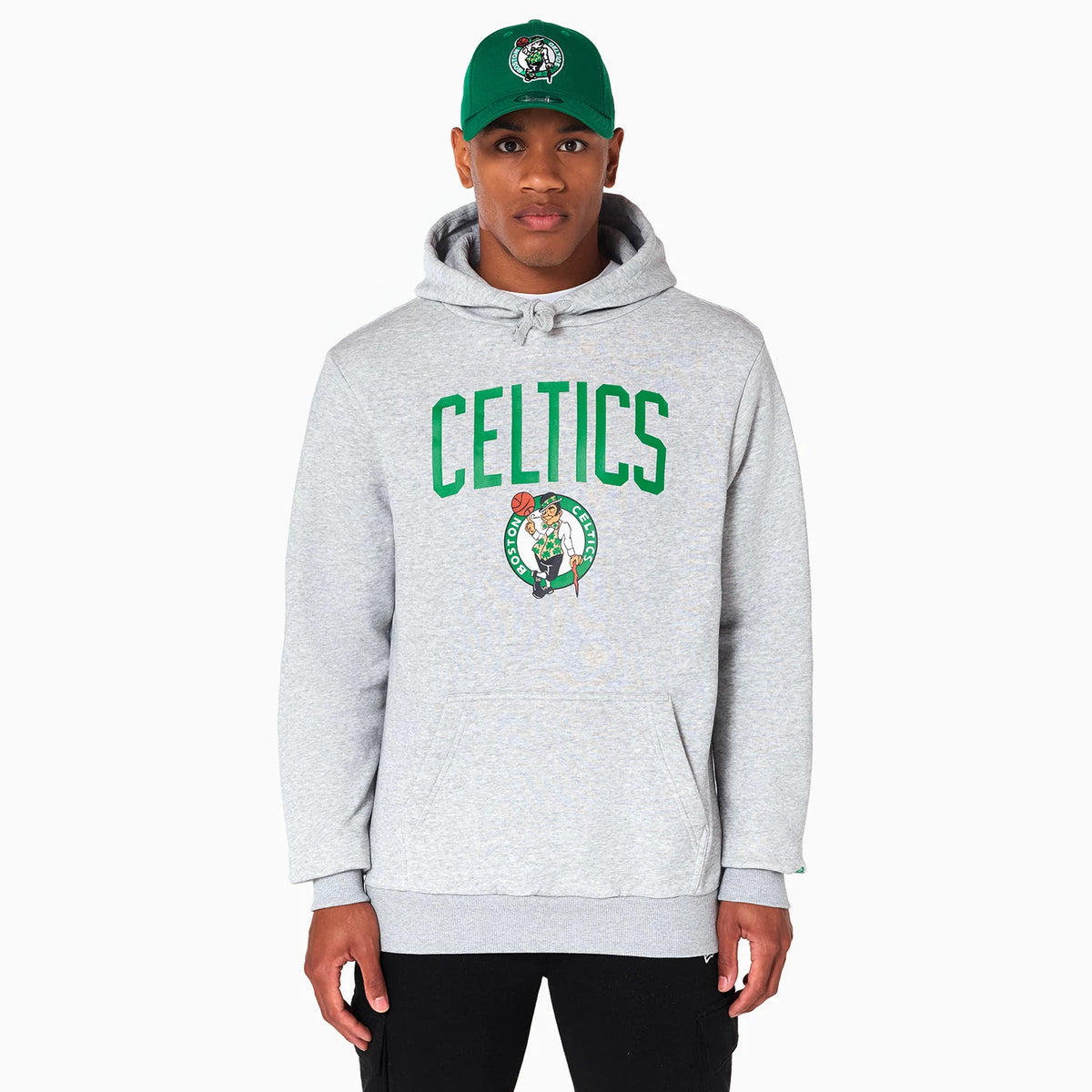 New Era Boston Celtics NBA Grey Pullover Hoodie, front view showing a light grey hoodie with green Celtics lettering across the chest, the team logo below, and a green cap with a similar logo worn by the model.