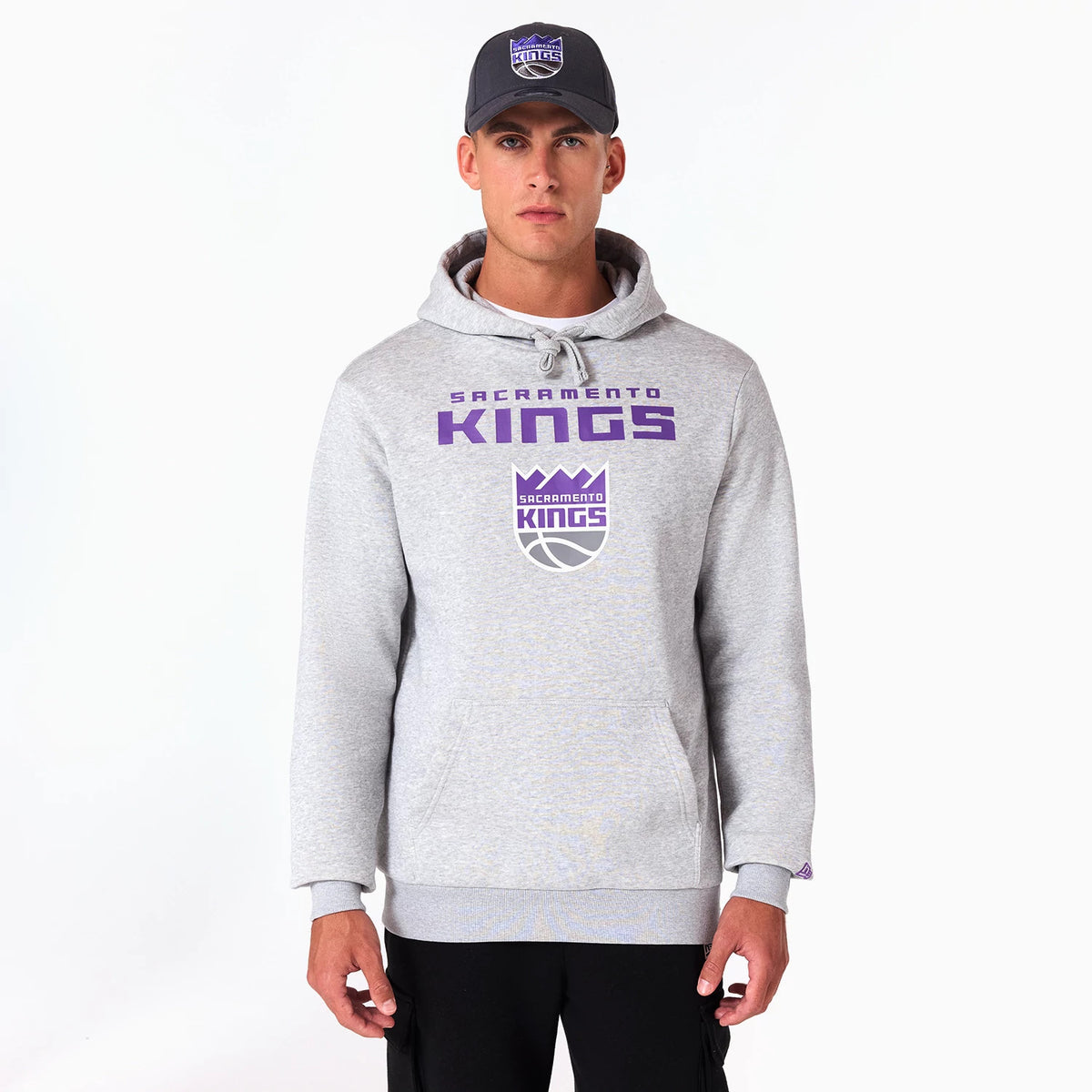 New Era Sacramento Kings NBA Grey Pullover Hoodie, front view showing the grey hoodie with purple text and logo on the chest, a drawstring hood and ribbed cuffs, worn by a model with a matching cap featuring a debossed team logo.