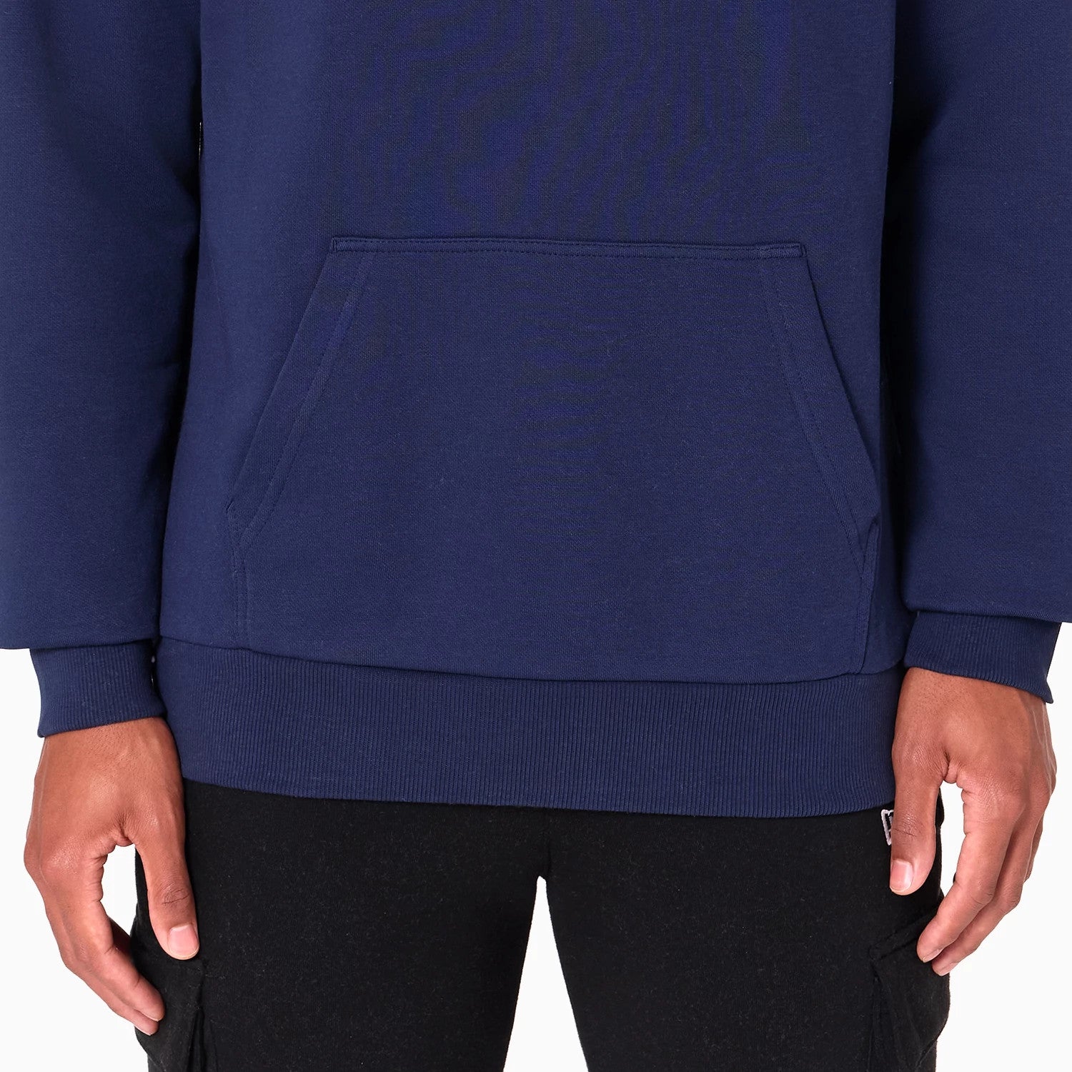 New Era Utah Jazz NBA Navy Pullover Hoodie, front view showing the navy body with a kangaroo pocket in the centre, long sleeves and a ribbed hem, worn by a person with hands resting beside the pocket.