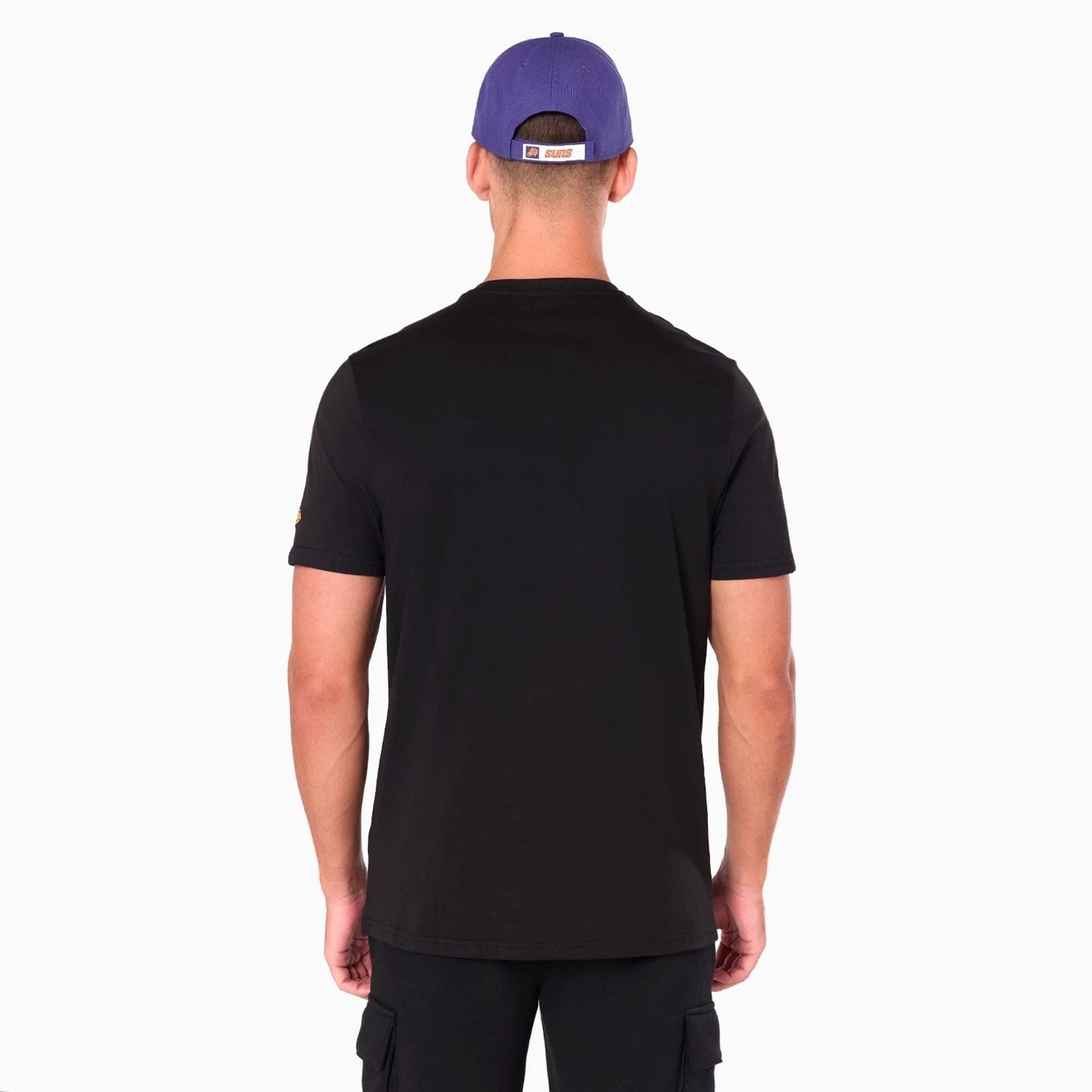 New Era Phoenix Suns NBA Black T-Shirt, rear view showing the plain black back of the shirt worn by a person with a purple cap, featuring an orange Suns label on the back of the cap above a white patch.