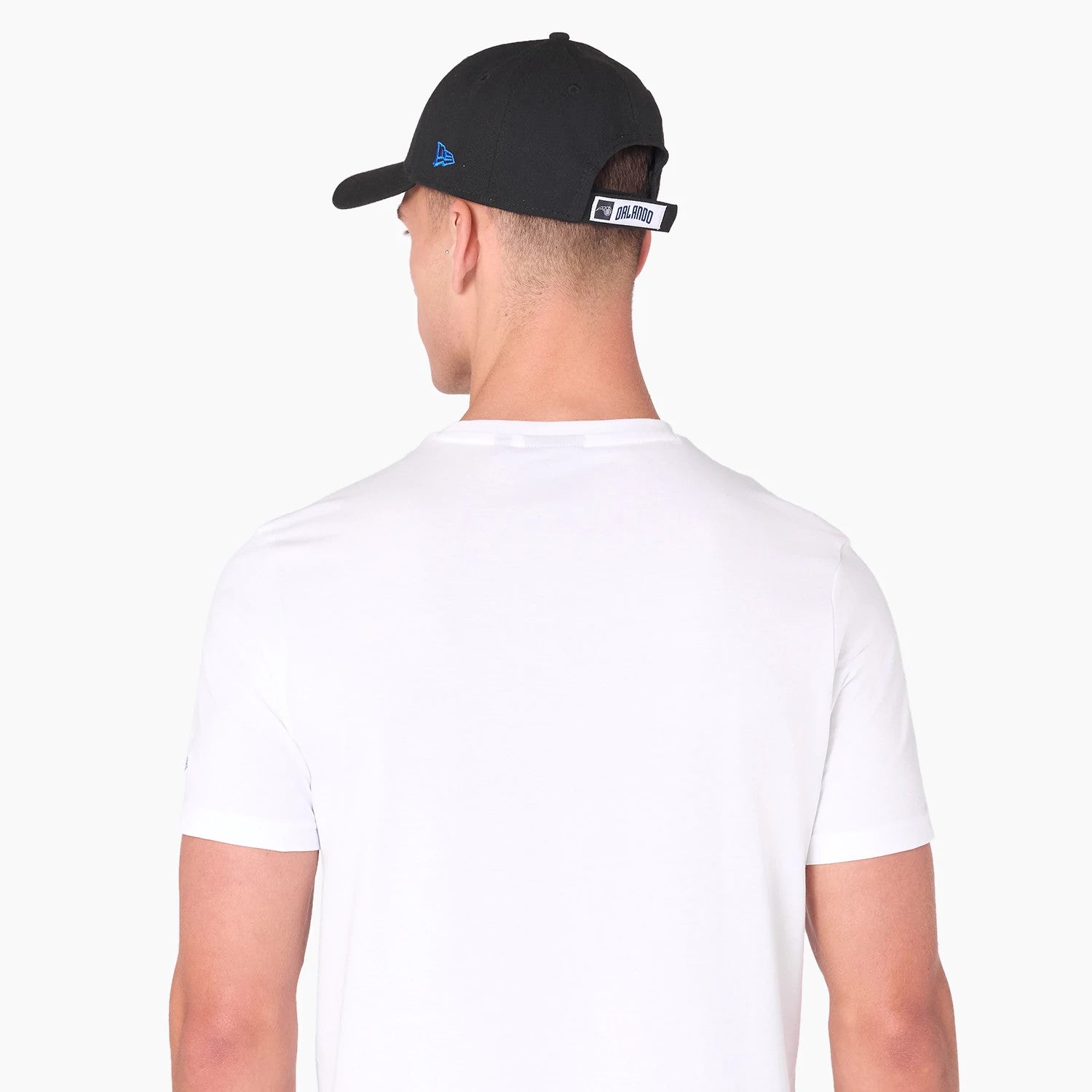 New Era Orlando Magic NBA White T-Shirt, rear view showing a plain white back and sleeves with a person wearing a black cap, featuring a raised New Era logo in blue and an Orlando tag on the strap at the back of the cap.