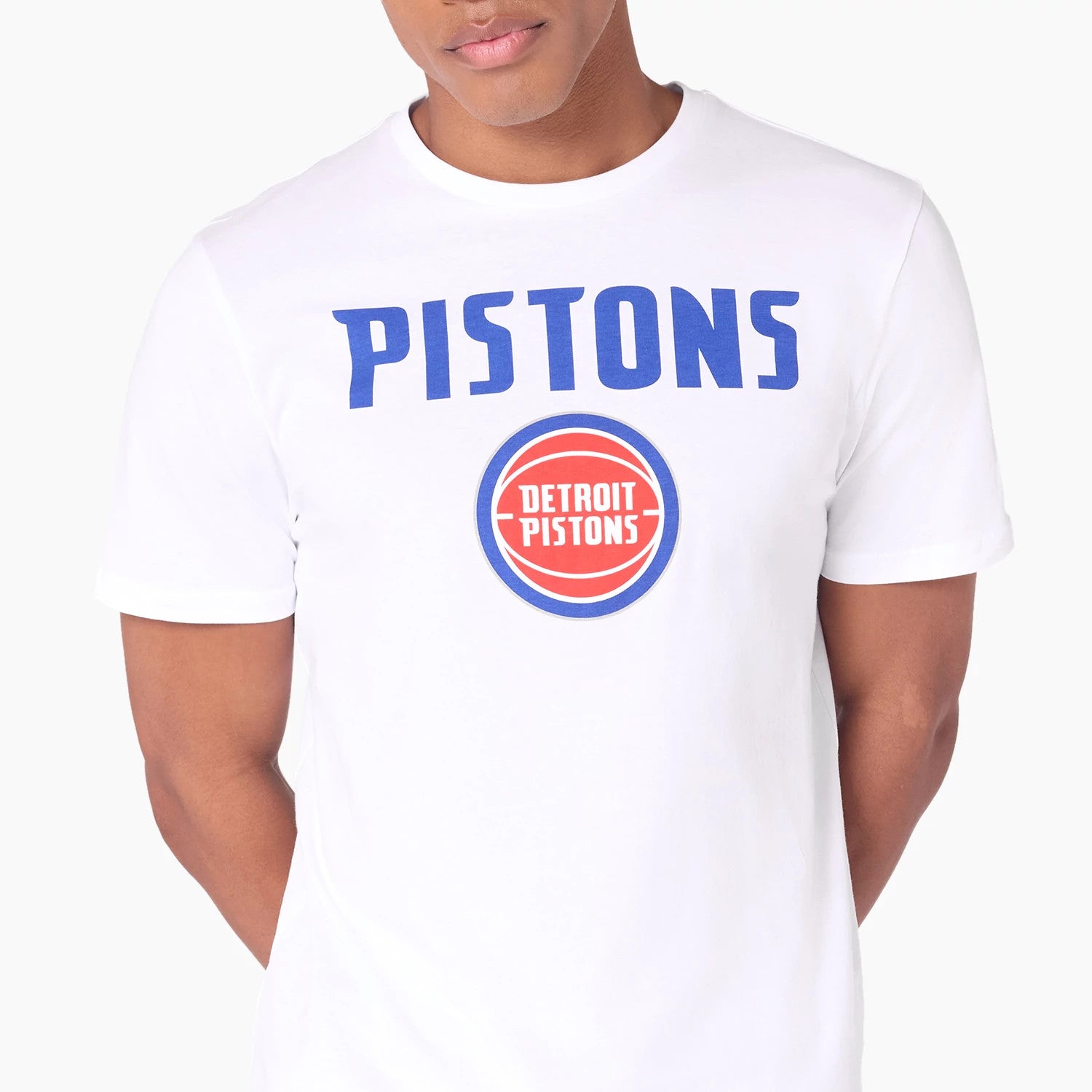 New Era Detroit Pistons NBA White T-Shirt, on-model view showing a white shirt with bold blue PISTONS text across the chest and a red and blue circular DETROIT PISTONS logo beneath, worn by a person from the waist up.