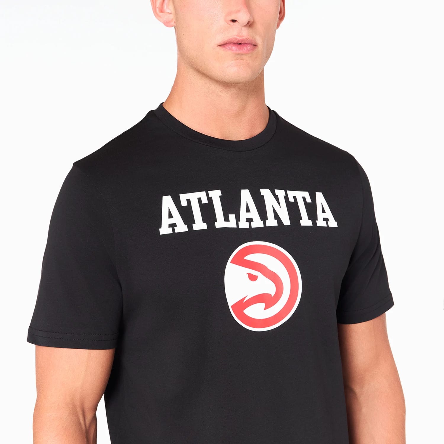 New Era Atlanta Hawks NBA Black T-Shirt, front view featuring bold white ATLANTA text across the chest above the large red and white Atlanta Hawks logo, on a black short-sleeve t-shirt worn by a model.