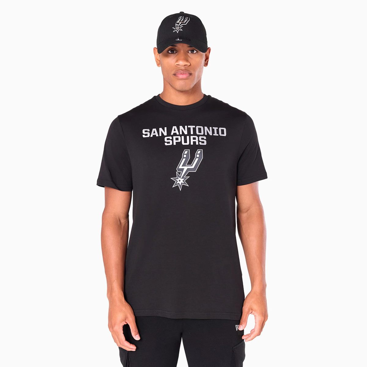 New Era San Antonio Spurs NBA Black T-Shirt, front view showing a black T-shirt worn by a model with the San Antonio Spurs logo and text printed in white across the chest, complemented by a black cap featuring a raised Spurs logo.